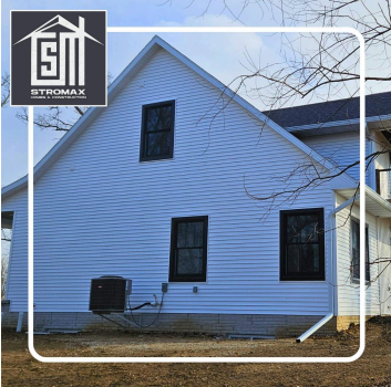 White-sided house with black windows, an AC unit, and gutter. The Stromax logo is in the corner.