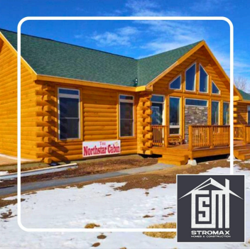 Log cabin with a green roof, snow on the ground, and a blue sky. 