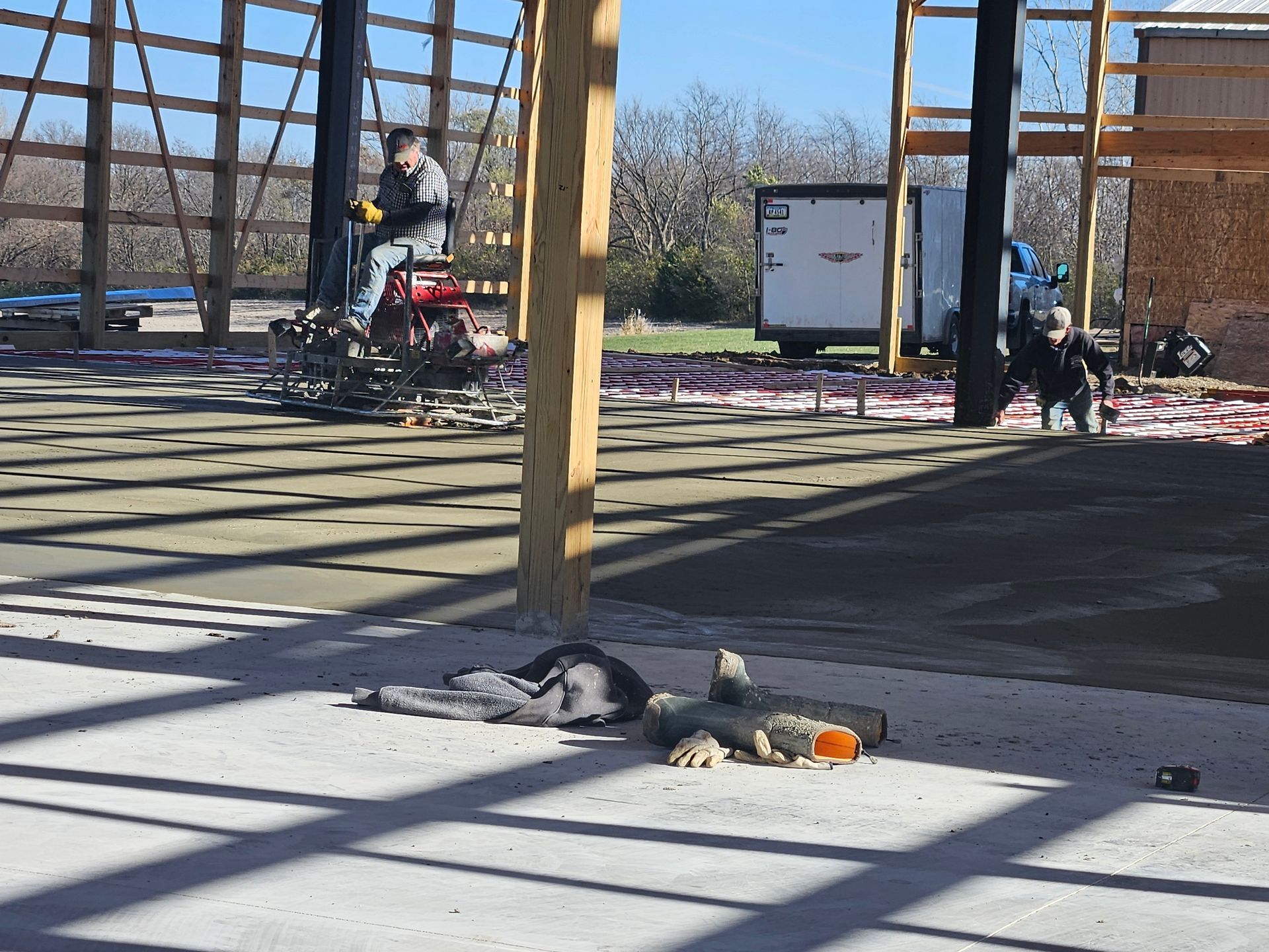 Construction site with workers, wooden framework, concrete floor, and equipment.