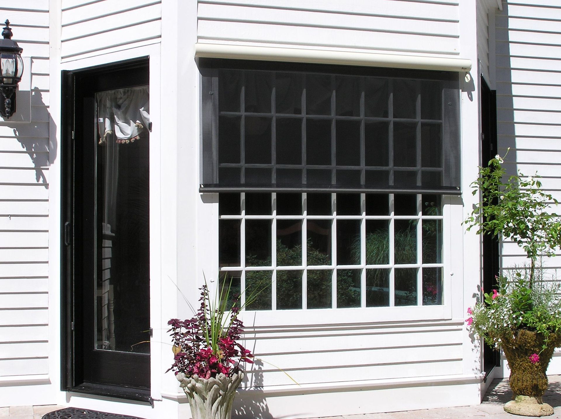 White house exterior with a black door, window, and a retractable black sunshade.
