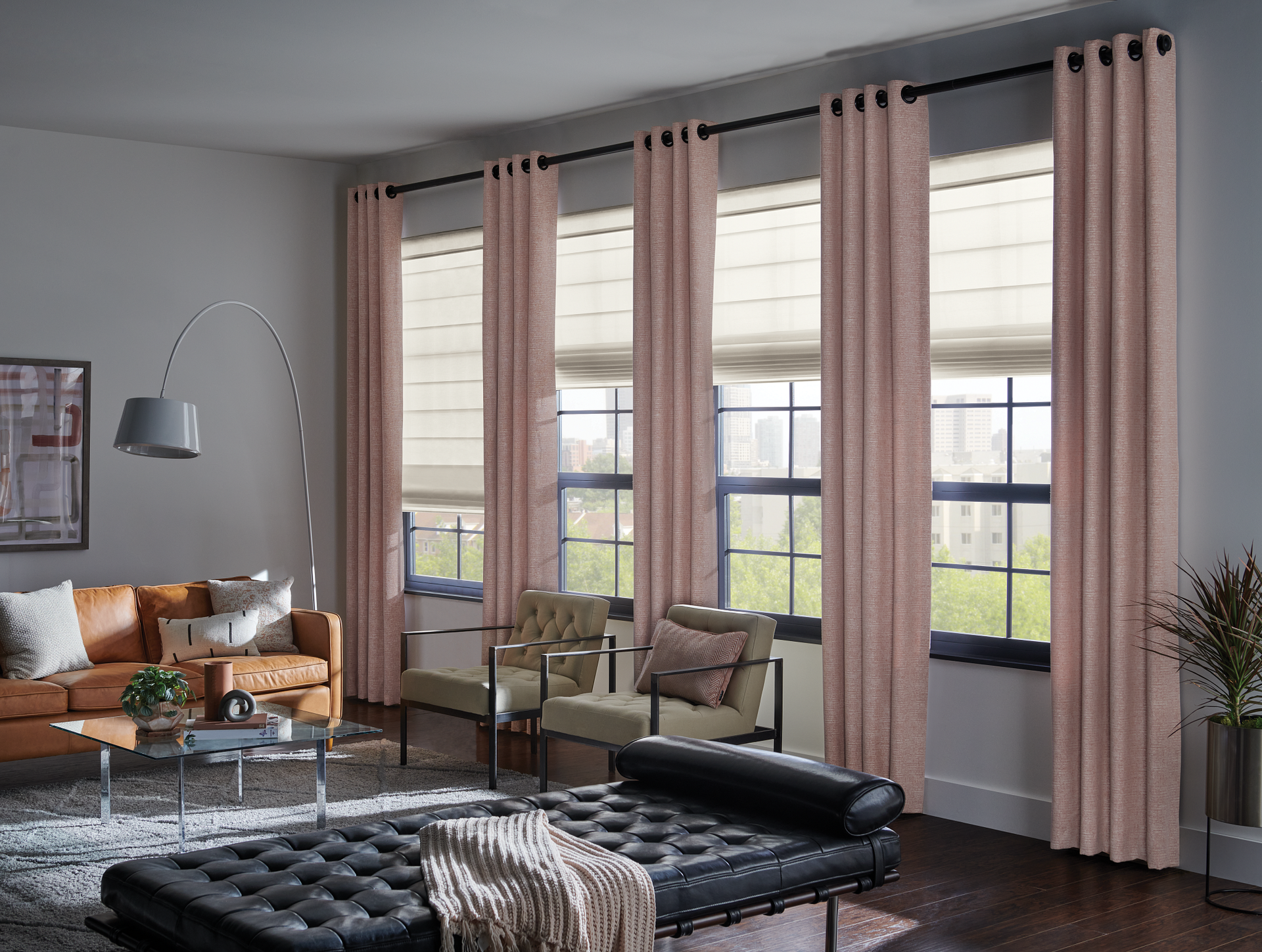 Living room with salmon curtains, neutral roman shades, leather furniture.