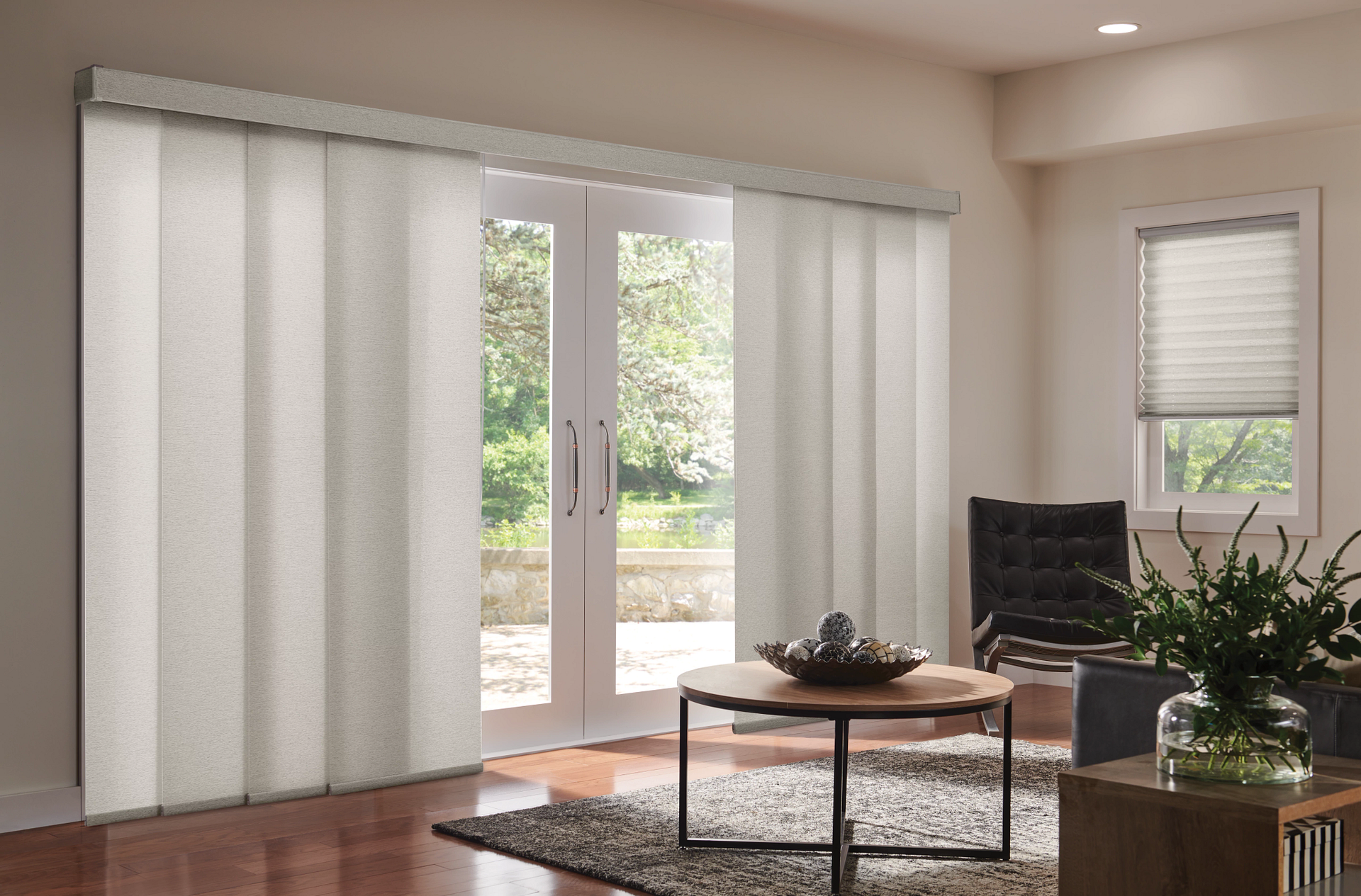 Cream-colored vertical blinds covering patio doors, with a small table, chairs, and a window on the right.