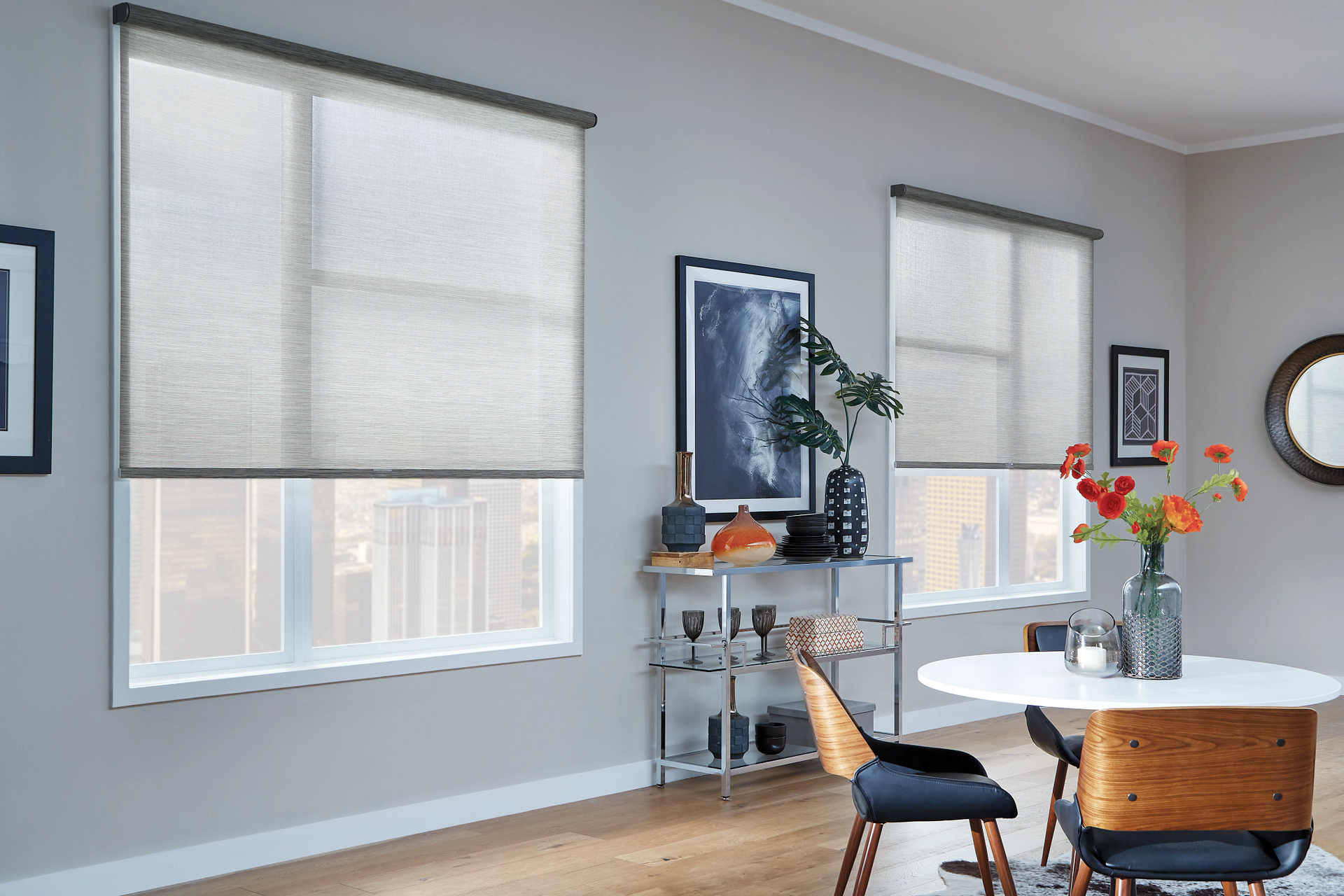 Dining room with windows, grey walls, white table, and closed light-colored roller blinds.