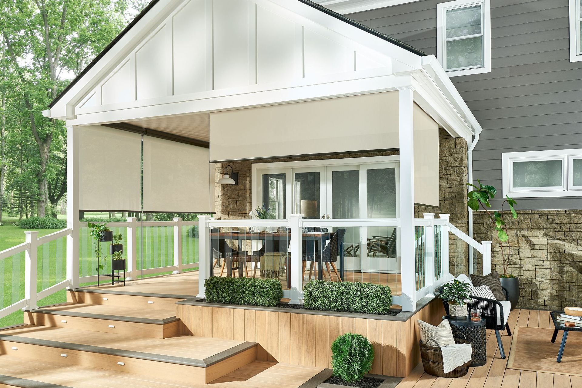 A beige deck with awnings extends from a house with a stone facade.