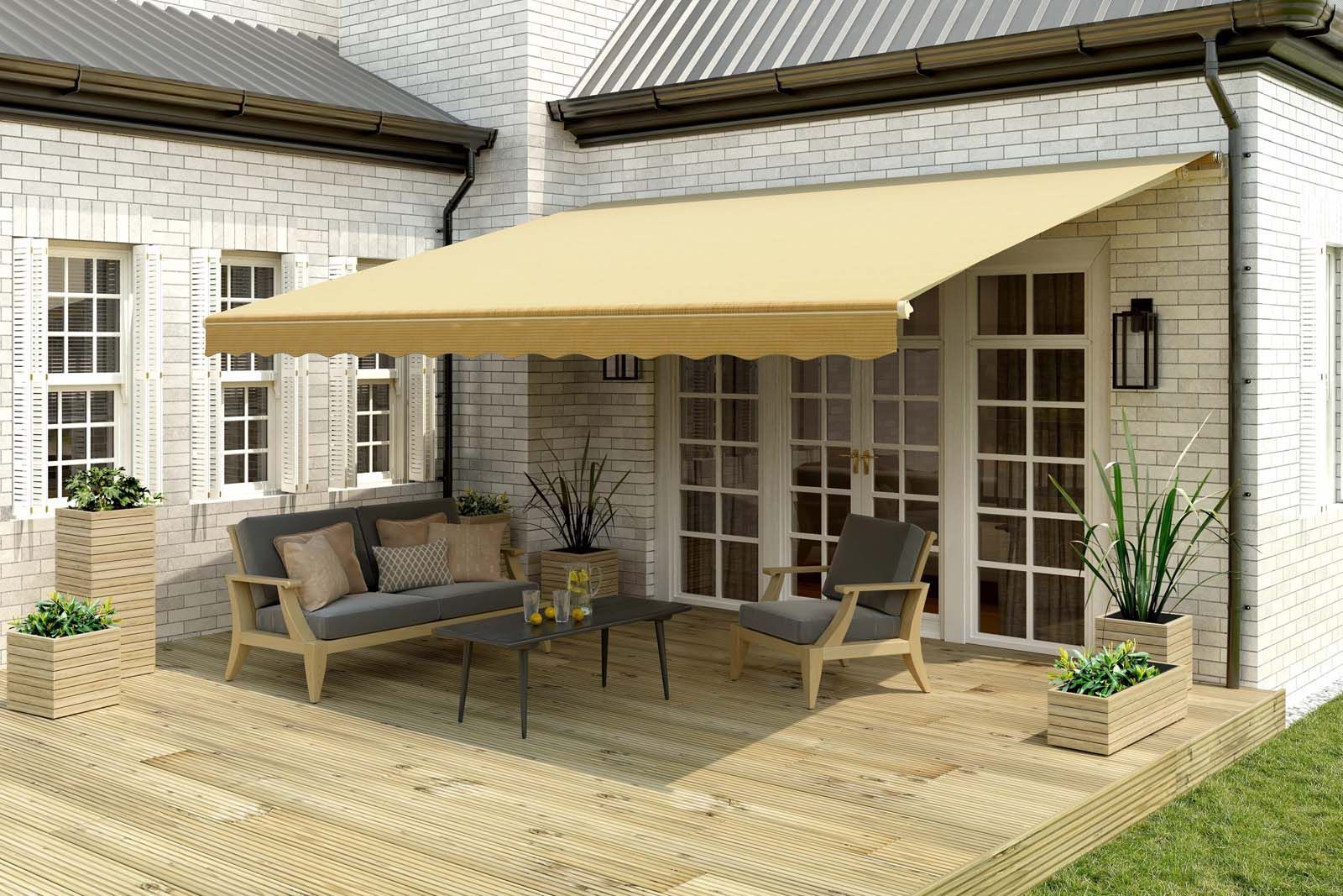 Beige awning over outdoor seating on a wooden deck, beside a white brick house.