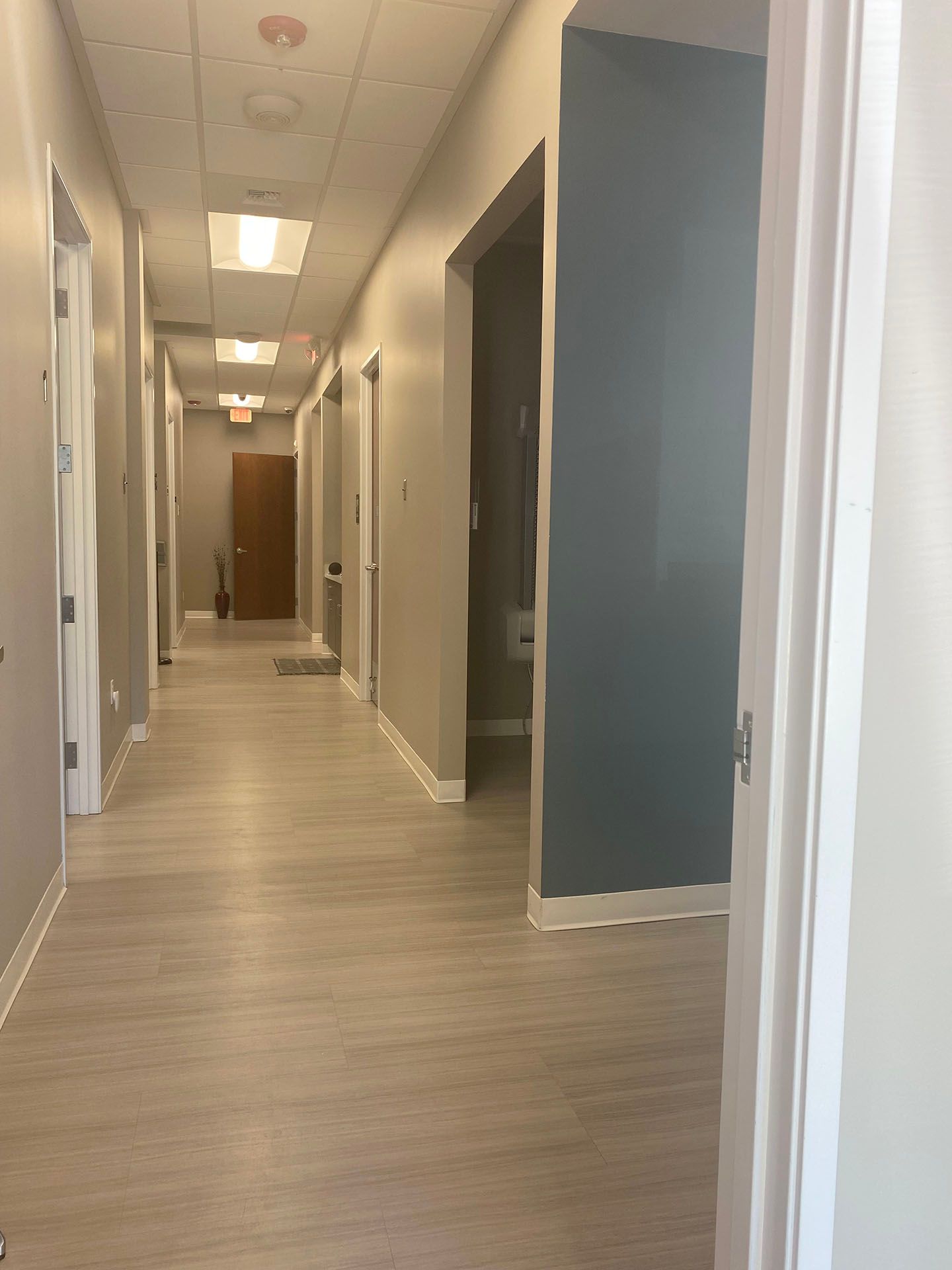 A long hallway in a building with a wooden floor and a lot of doors