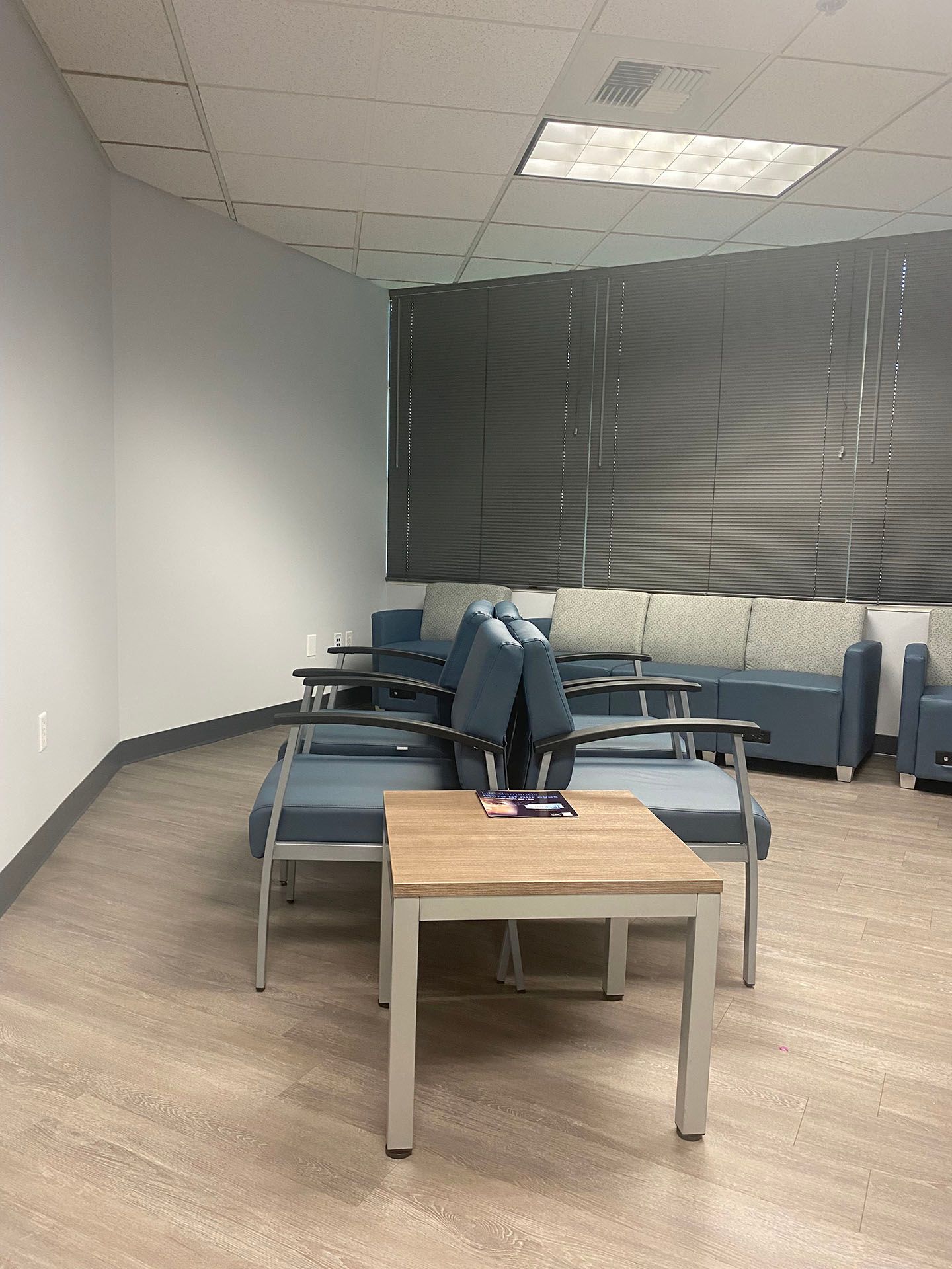 A waiting room with a table, chairs, and a couch