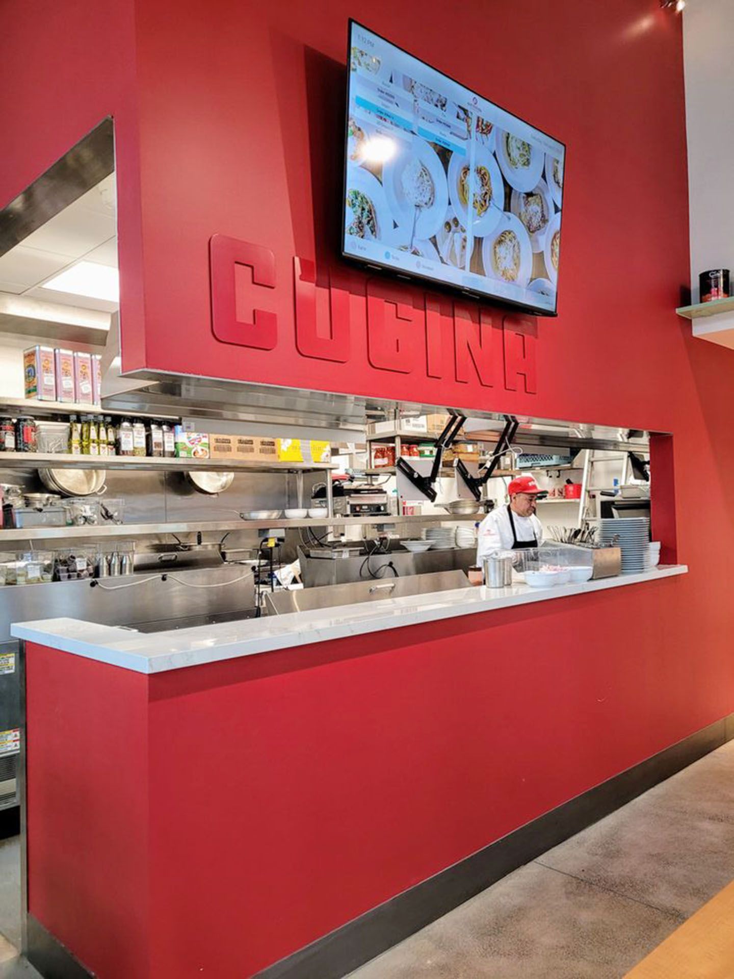 A chef is standing behind a counter in a restaurant kitchen
