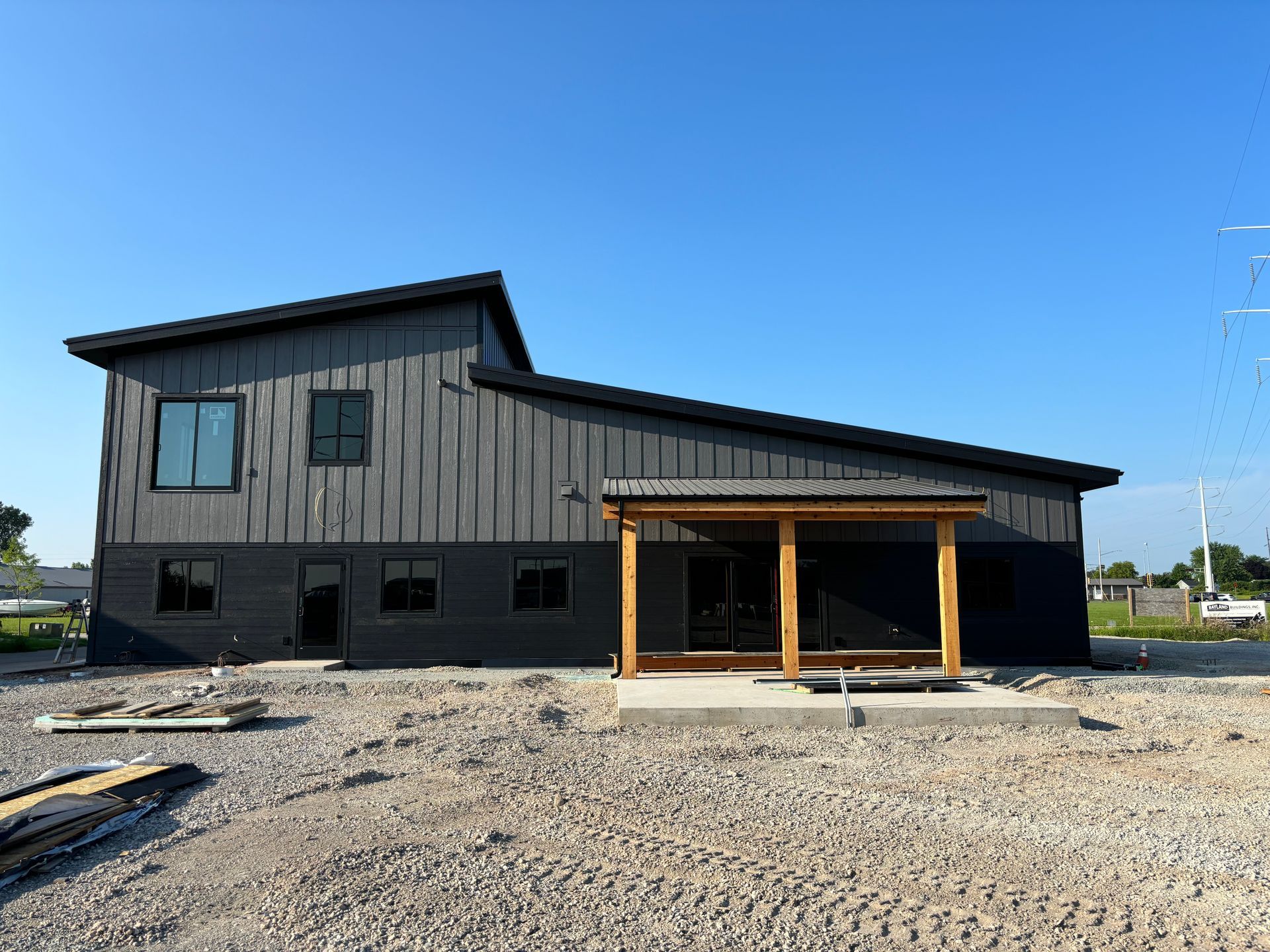 A large building with a porch is sitting on top of a dirt field.