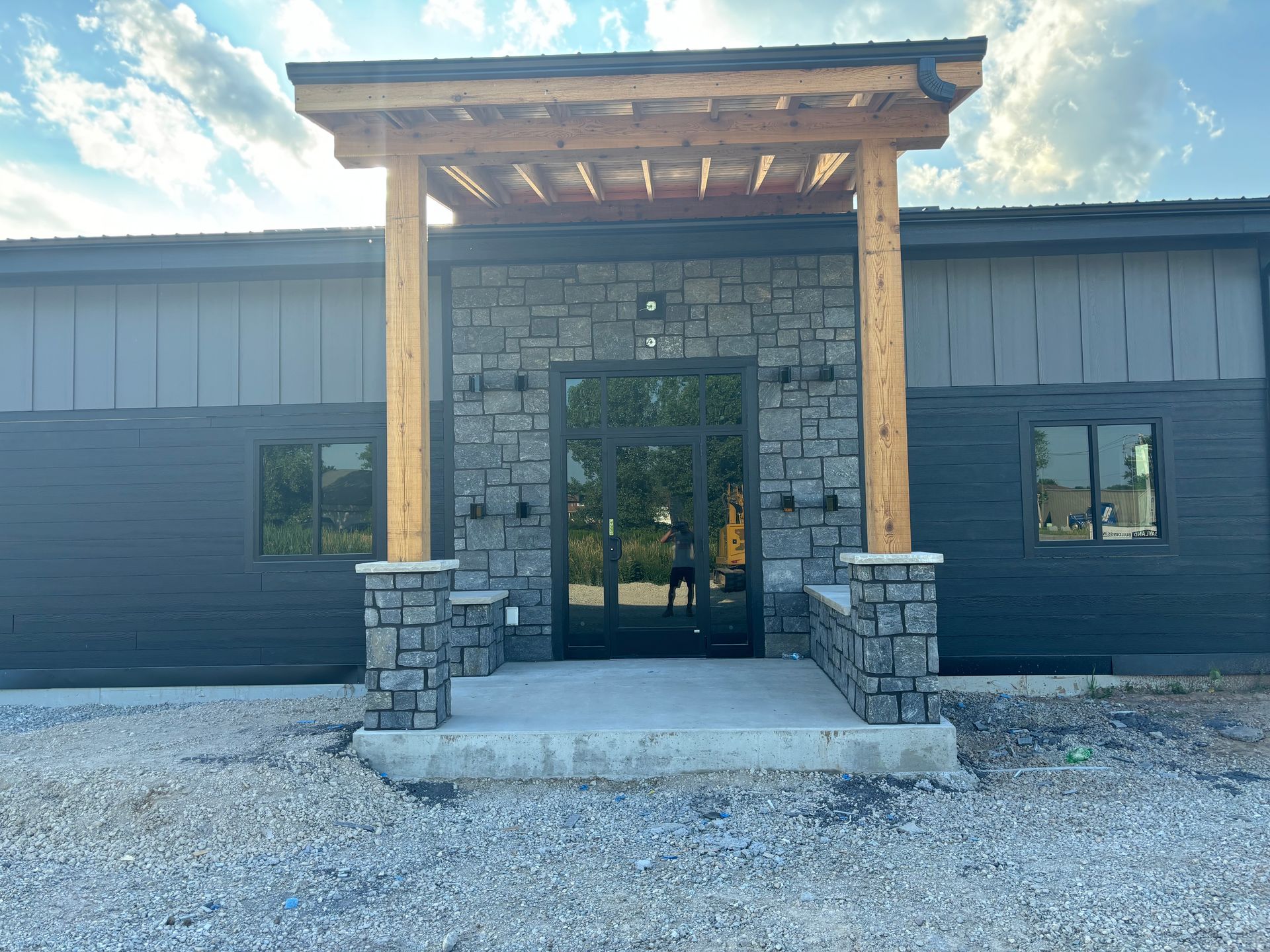A black building with a stone entrance and a wooden porch.