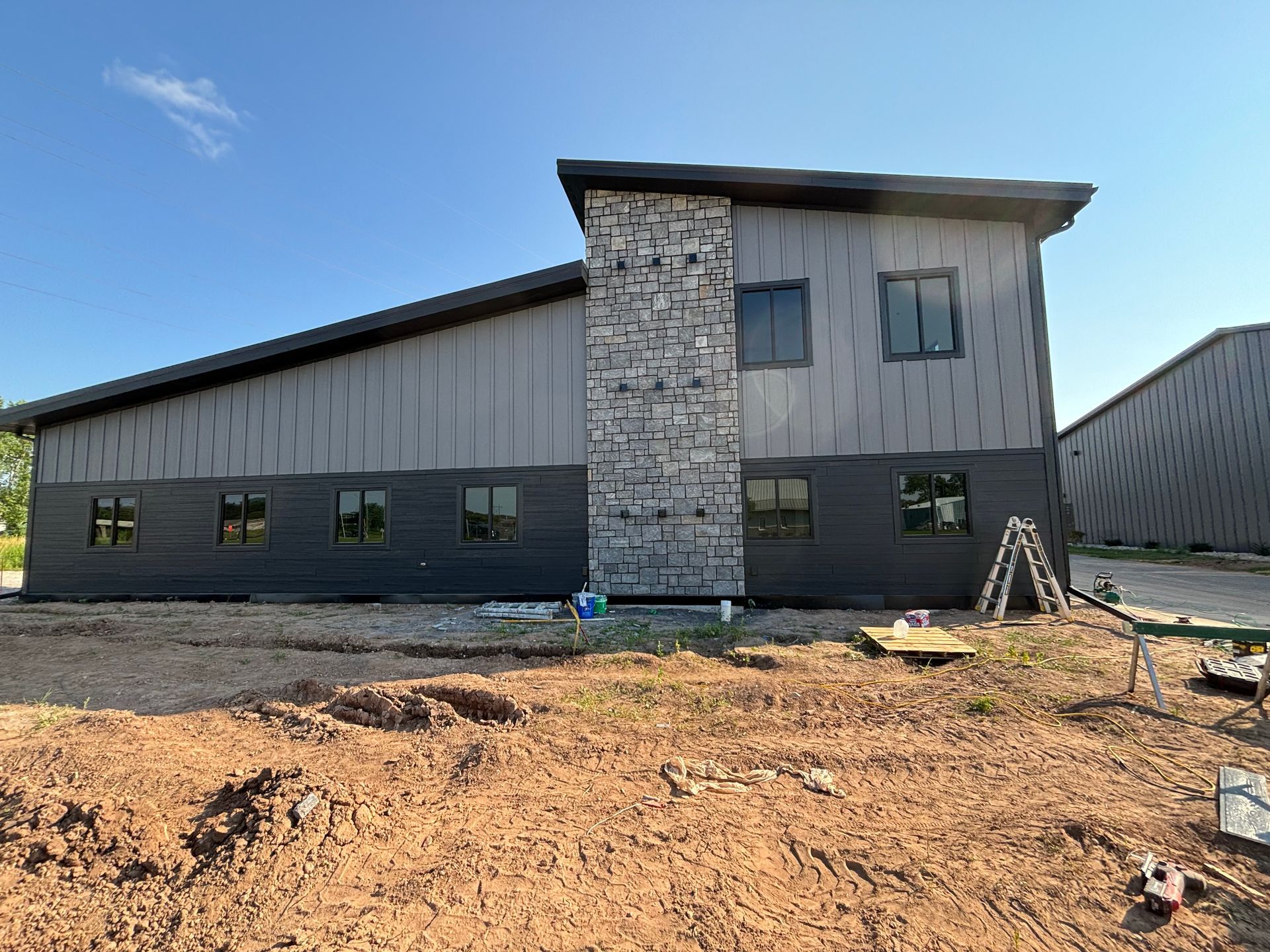 A large building with a stone fireplace is being built in a dirt field.
