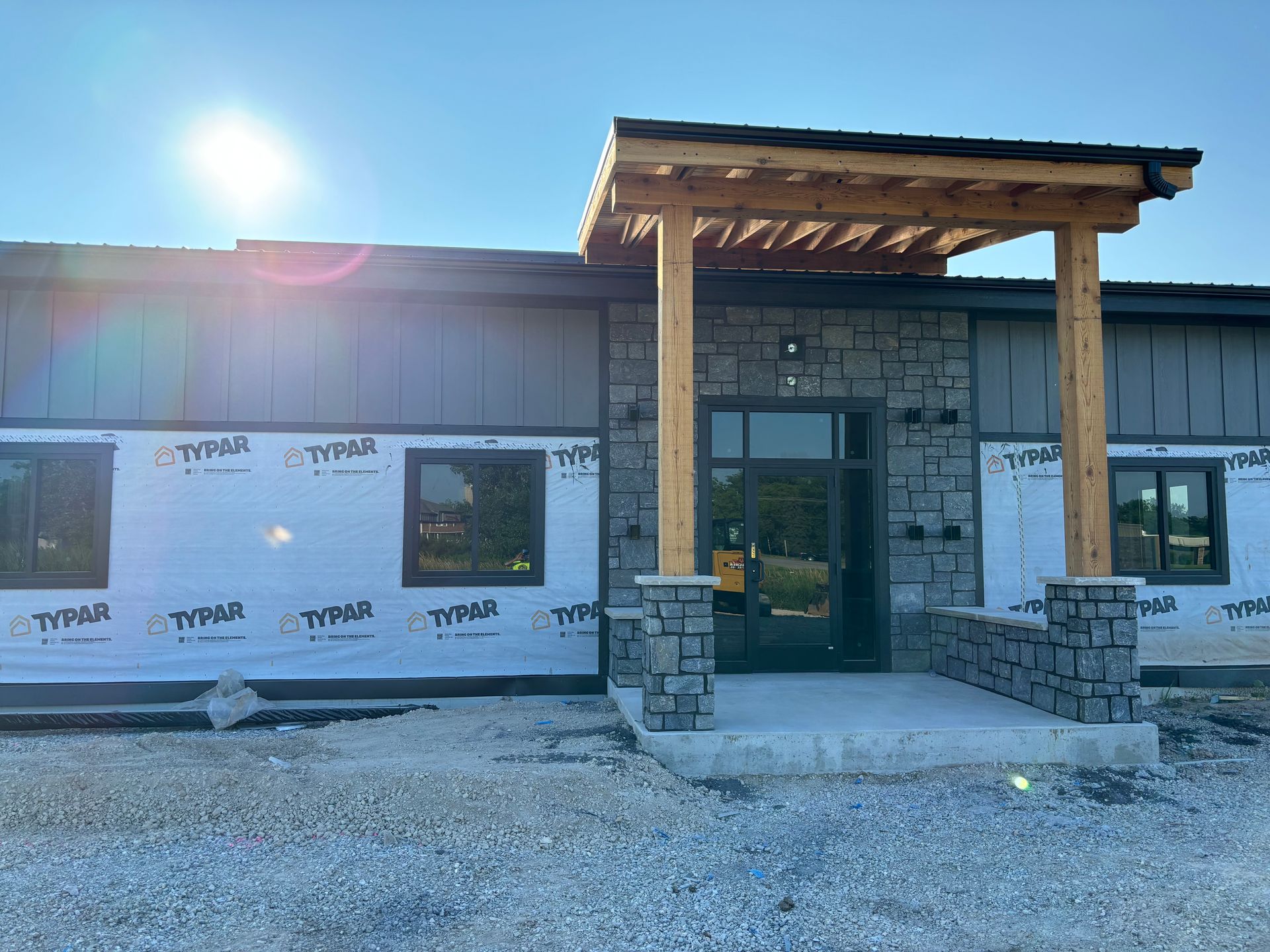 A building under construction with a porch and a lot of windows.