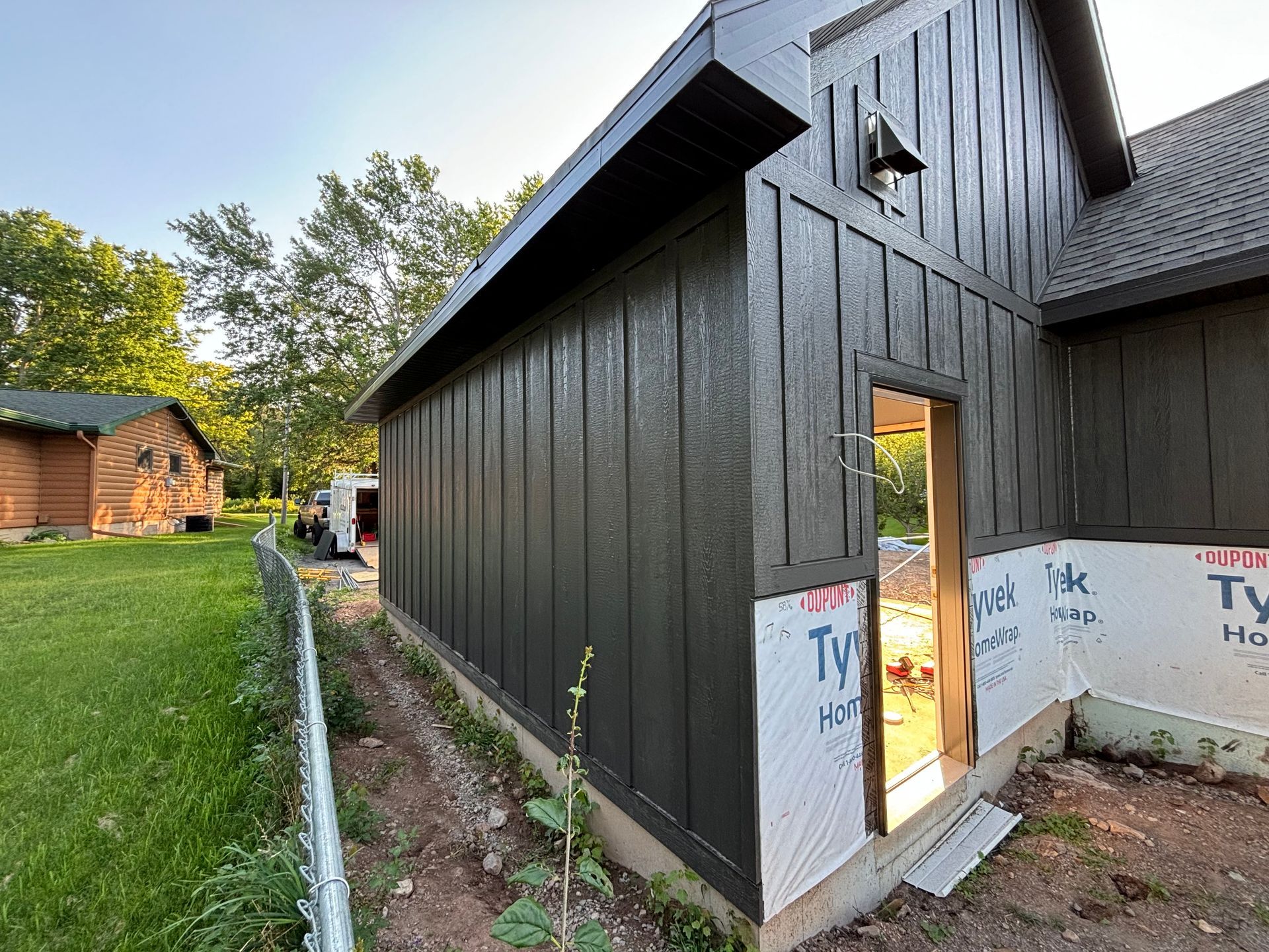 A house with a black siding and a door is being built.