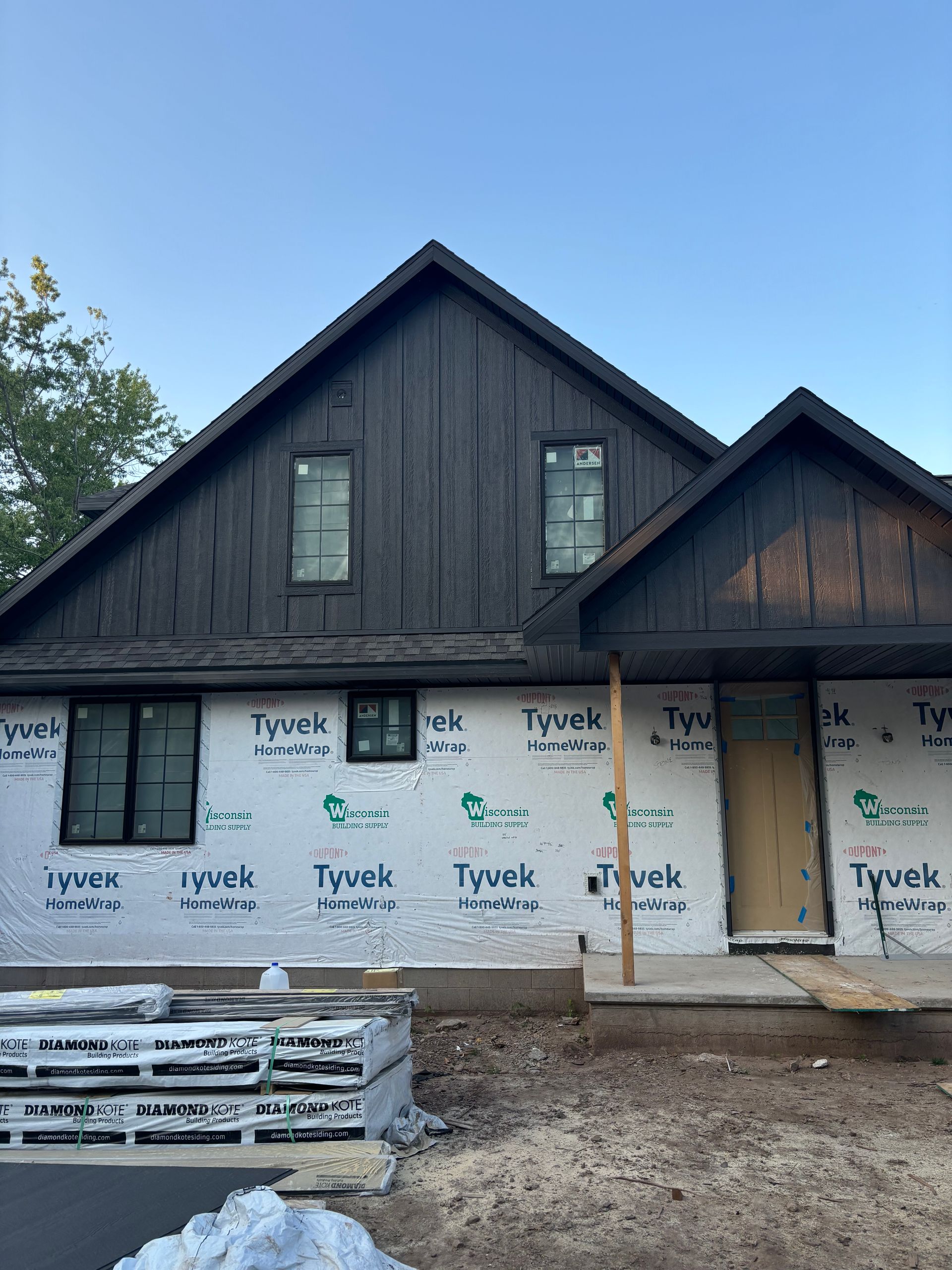 A house is being built with a black roof and white siding.