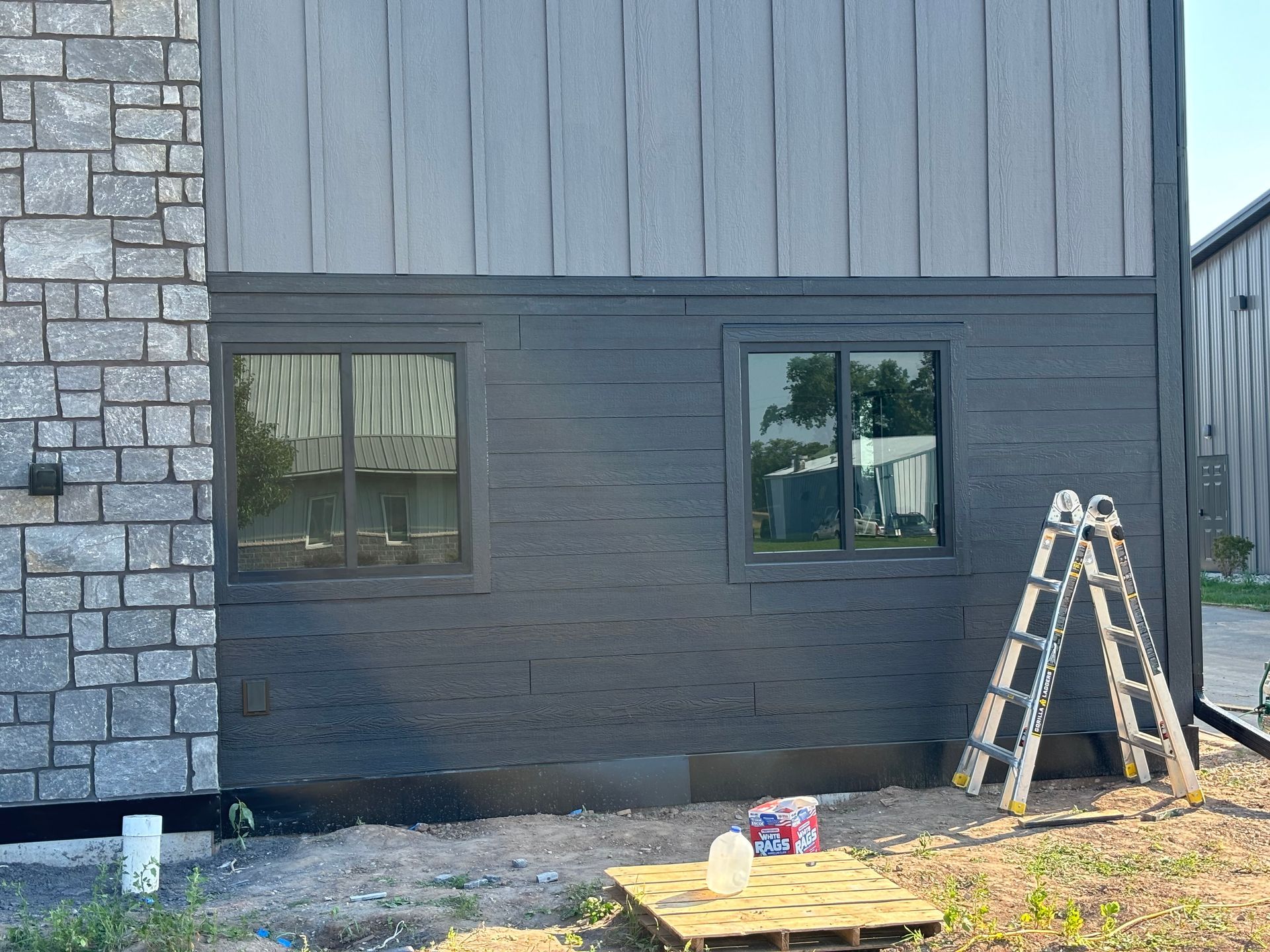 A ladder is sitting on a wooden pallet in front of a house that is being painted.