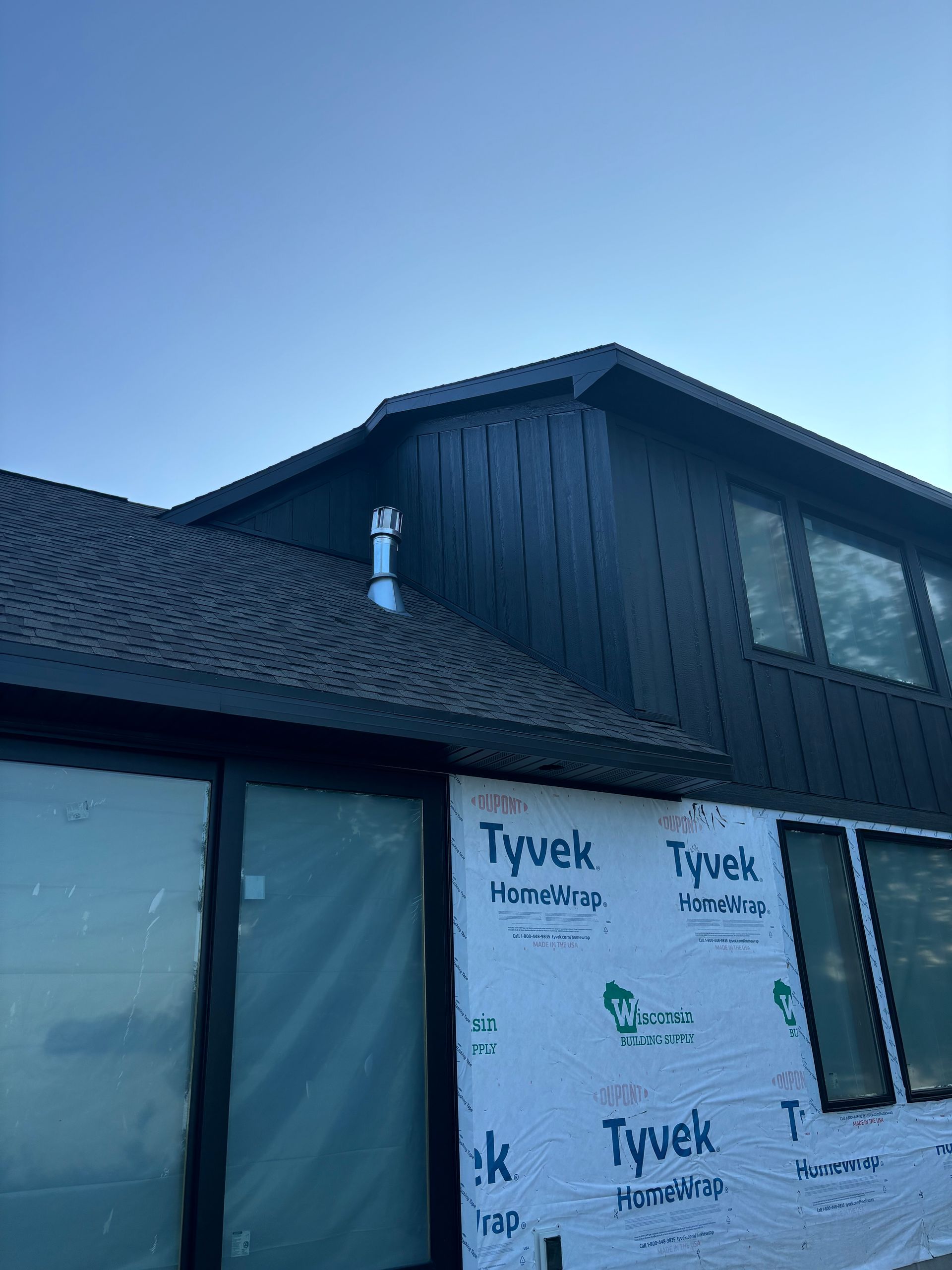 A black house with a roof and windows is being built.
