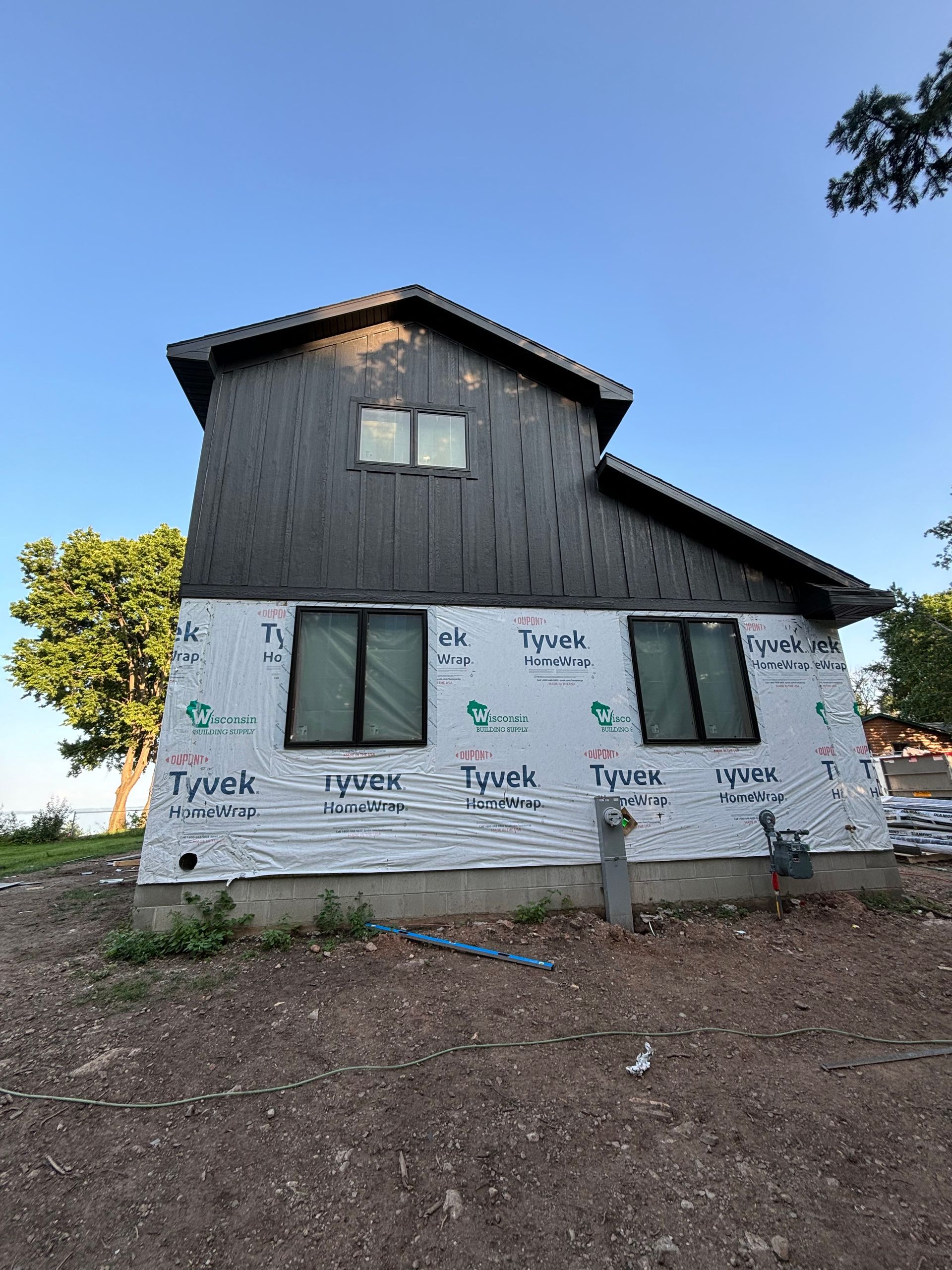 A house with a lot of windows is sitting on top of a dirt field.