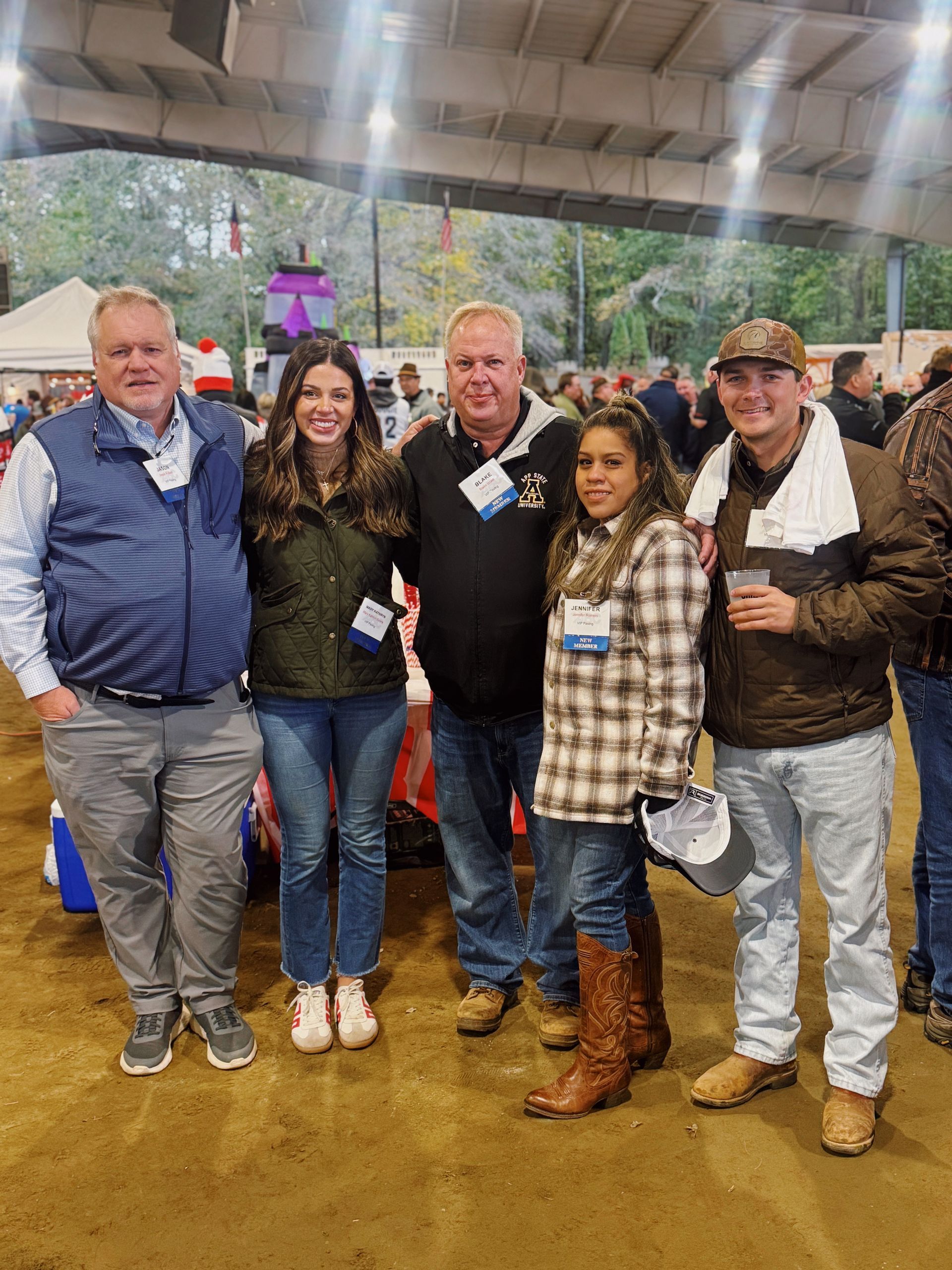 Group of five people smiling, posing in a covered outdoor setting.