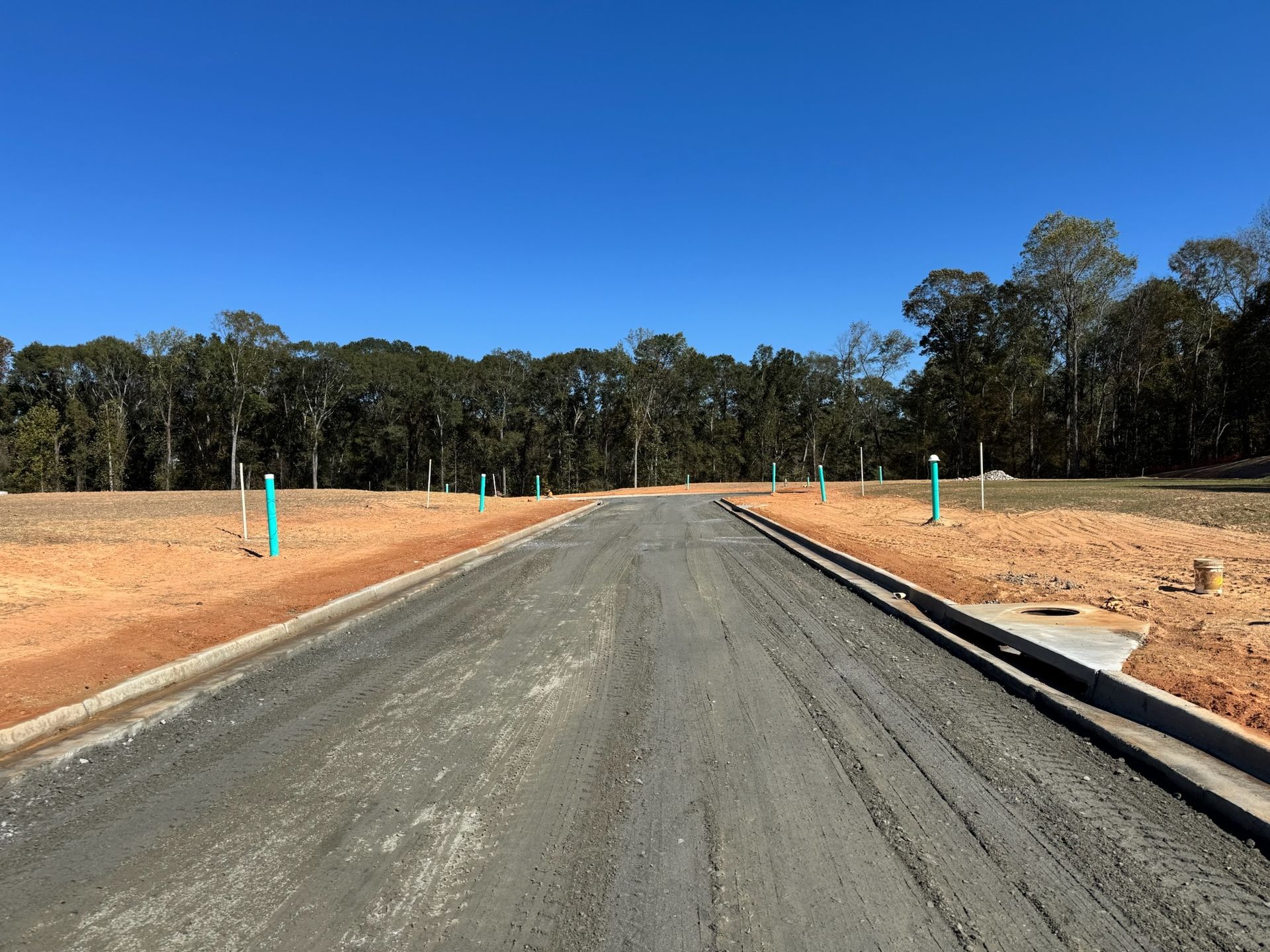 Gravel road in a new residential development under a clear blue sky, with trees in the background.