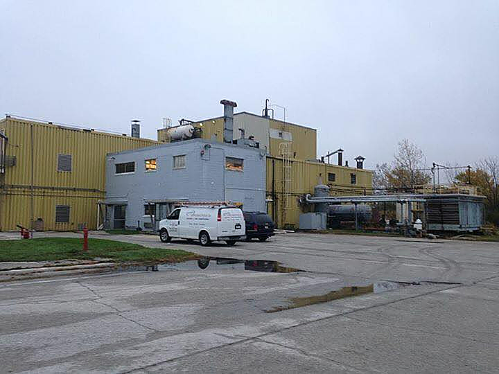 A white van is parked in front of a large building.