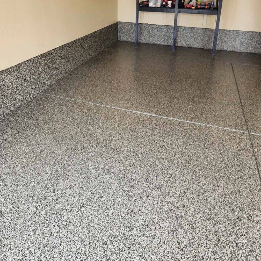 Speckled gray garage floor with a low wall and storage shelves in the background