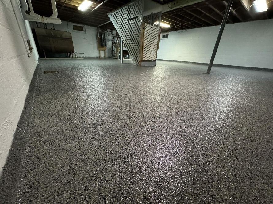 Empty indoor room with speckled gray floor, white walls, and exposed ceiling beams