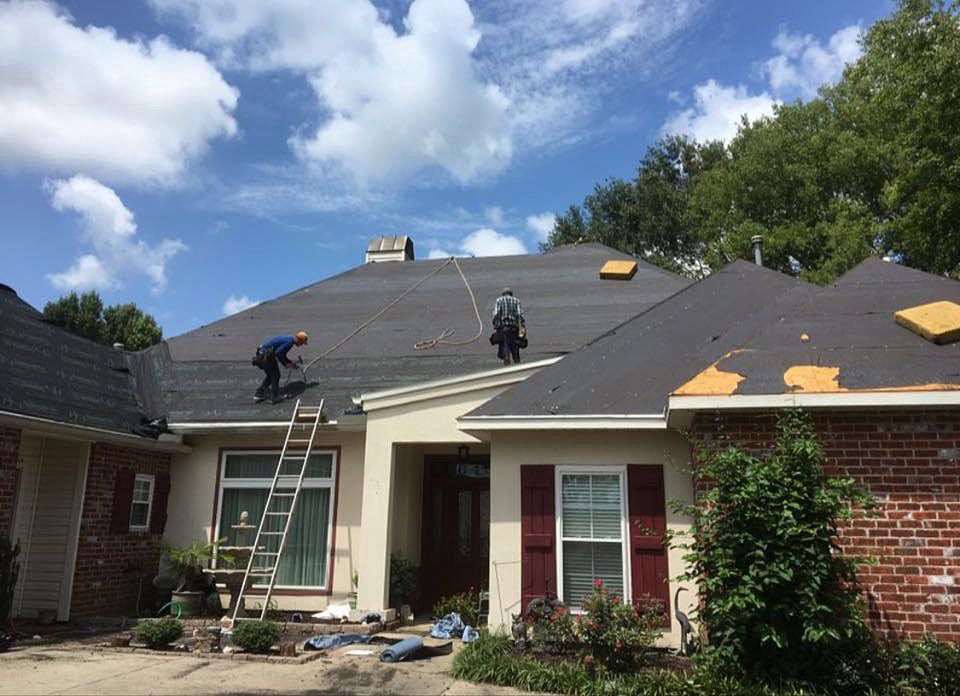 Two men are working on the roof of a house.