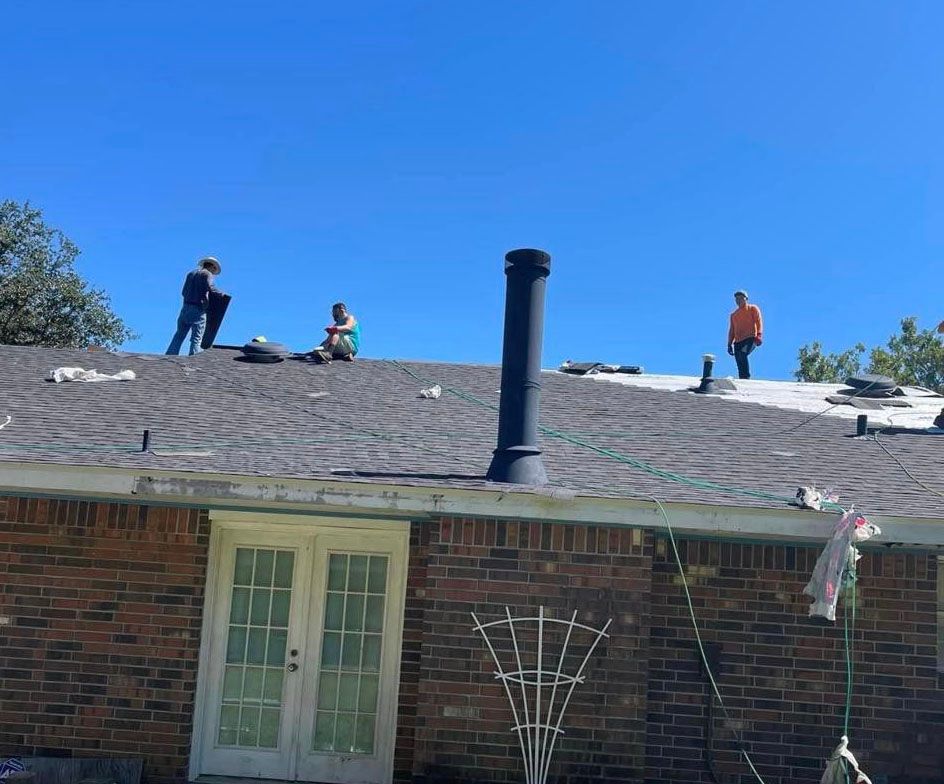 A group of people are working on the roof of a house.
