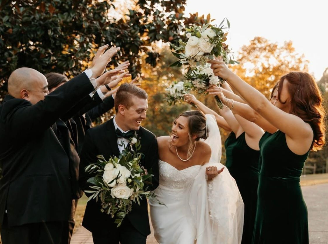 A bride and groom are being congratulated by their wedding party.