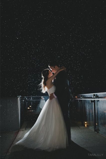 A bride and groom kissing under a starry sky