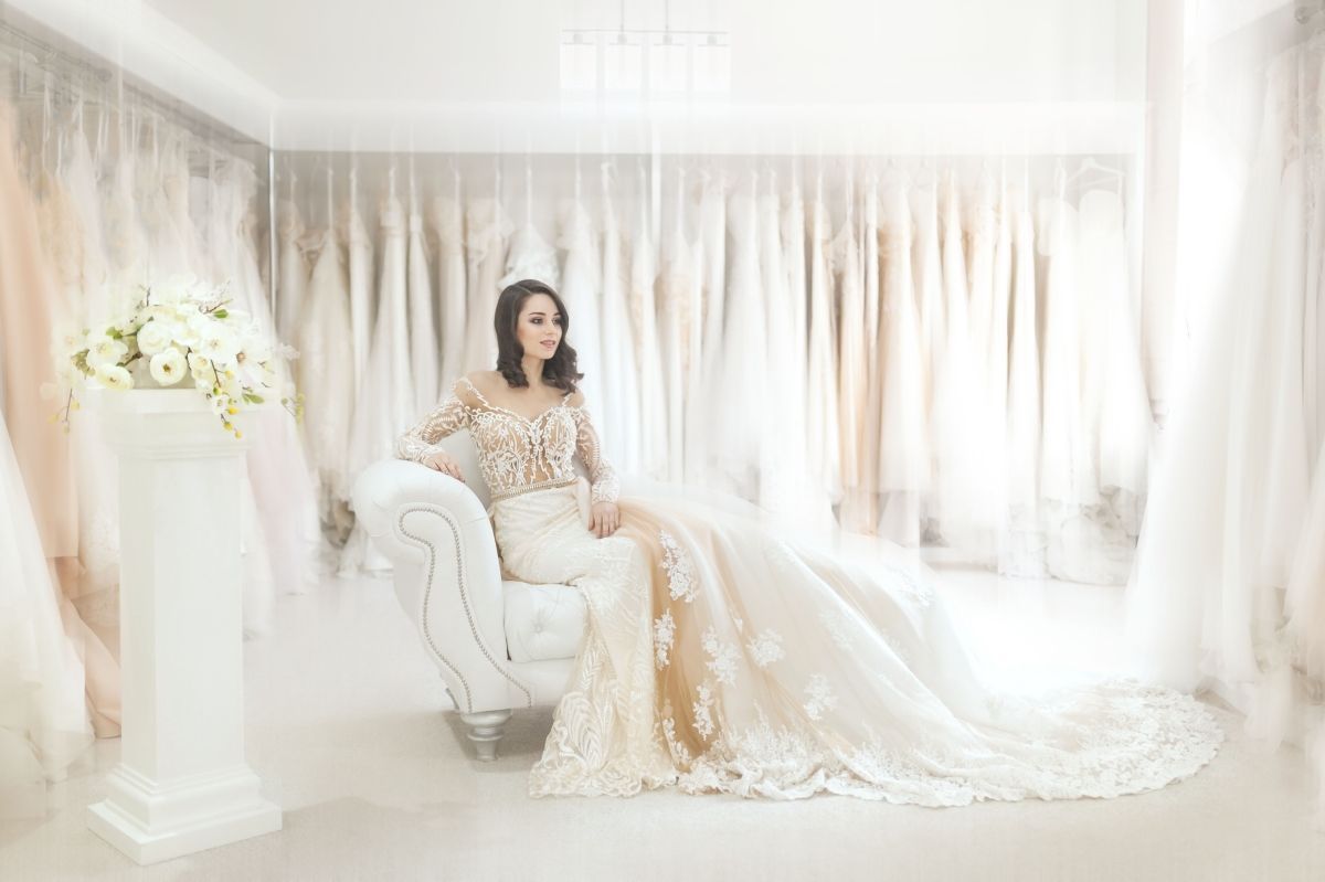 A woman in a wedding dress is sitting on a couch in a bridal shop.