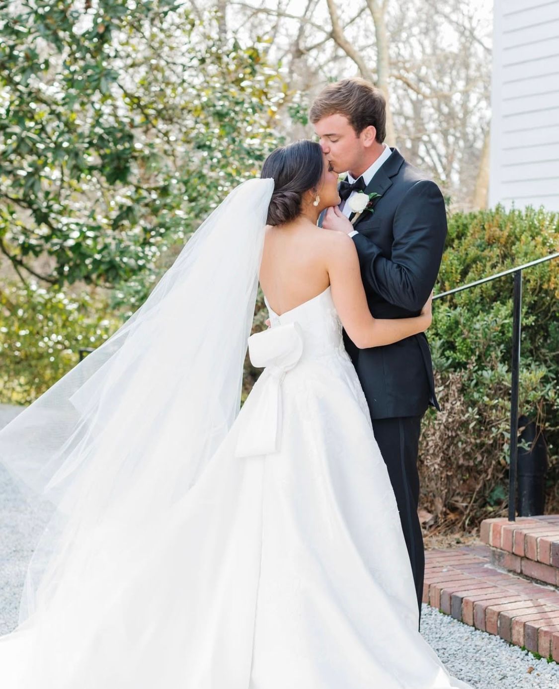 A bride and groom are kissing in front of a building.