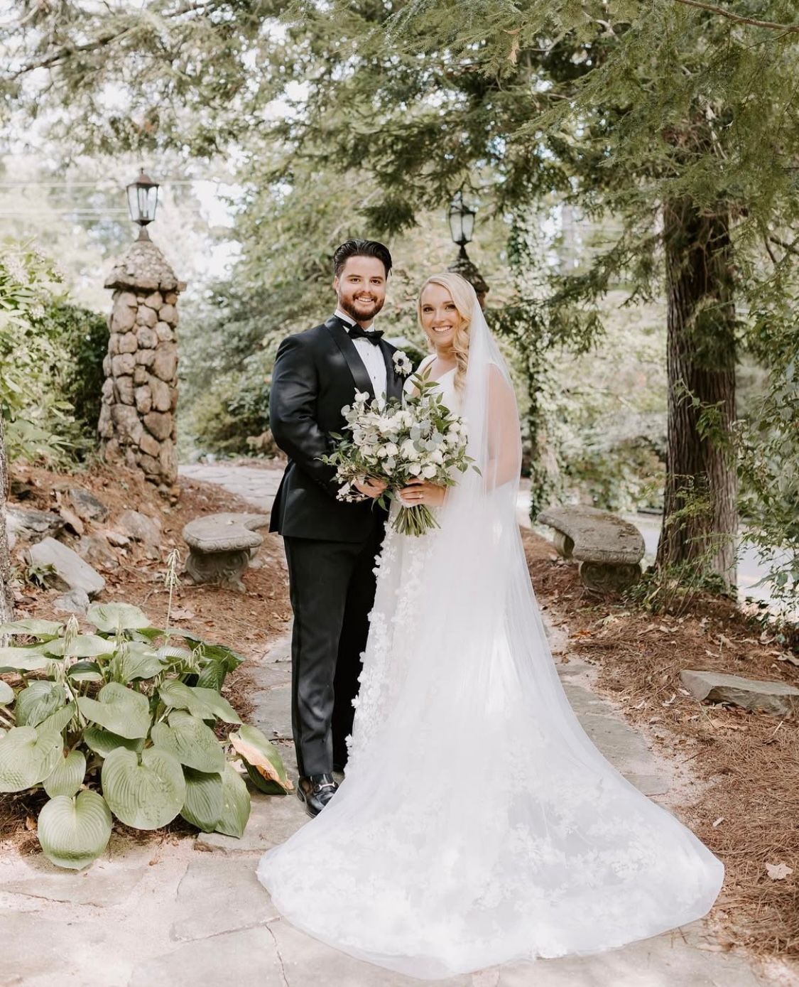 A bride and groom are posing for a picture in the woods.