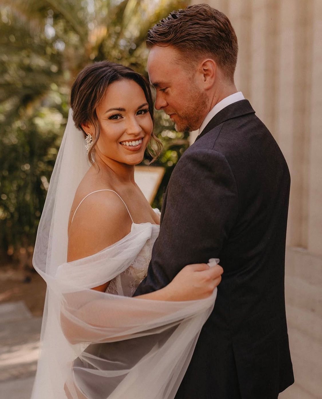 A bride and groom are posing for a picture on their wedding day.