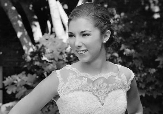 A woman in a wedding dress is smiling in a black and white photo.