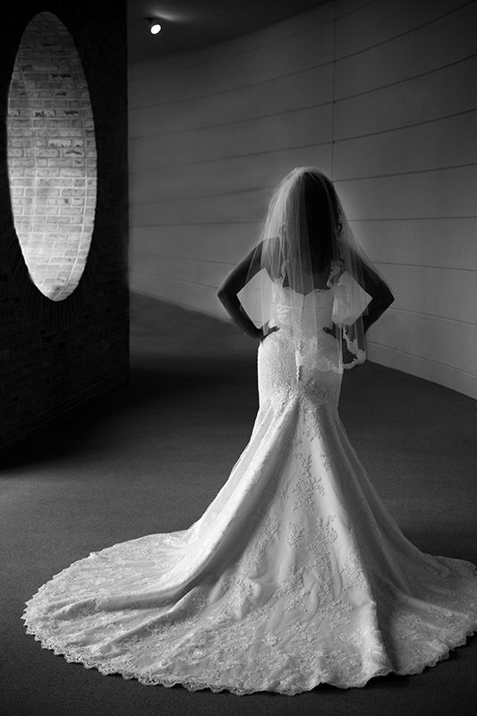 A woman in a wedding dress is standing in front of a mirror.