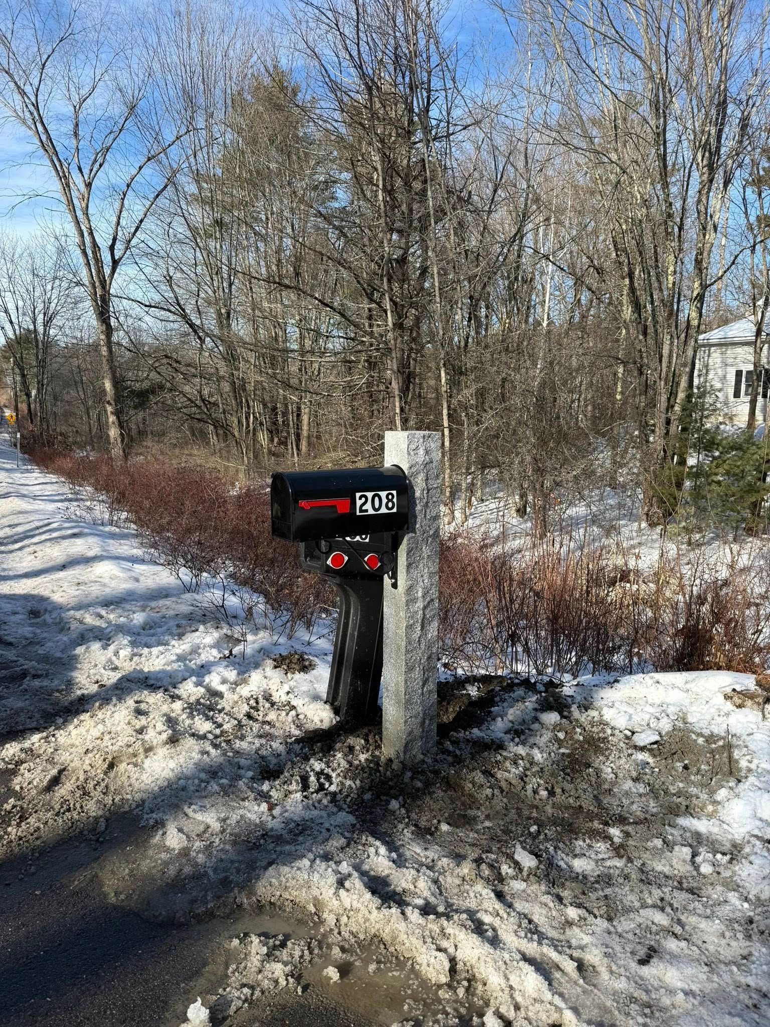 Mailbox with address 2818 on a stone post, next to a snowy road.