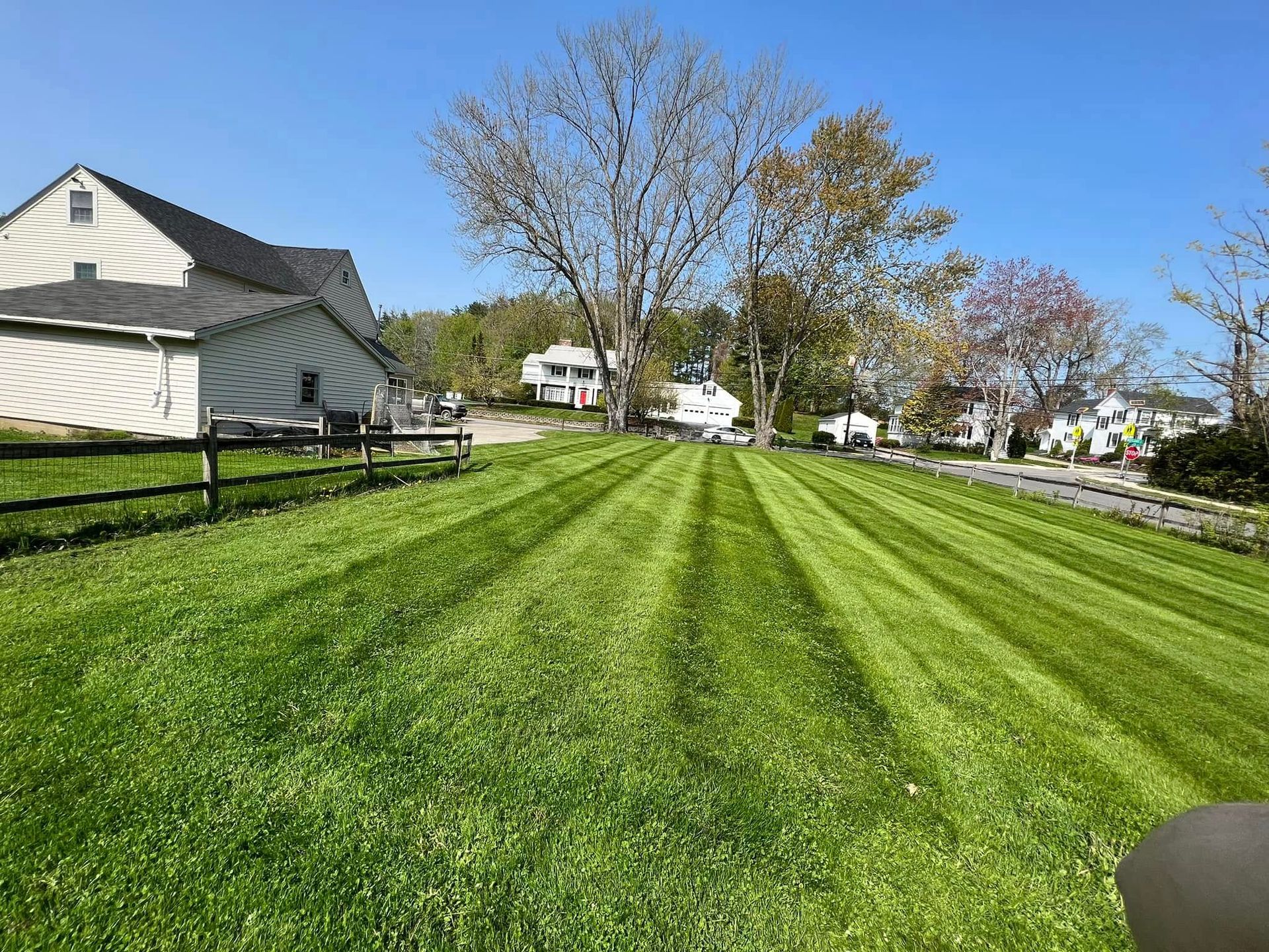 Lawn with freshly cut stripes. Barn and houses in background. Blue sky overhead.