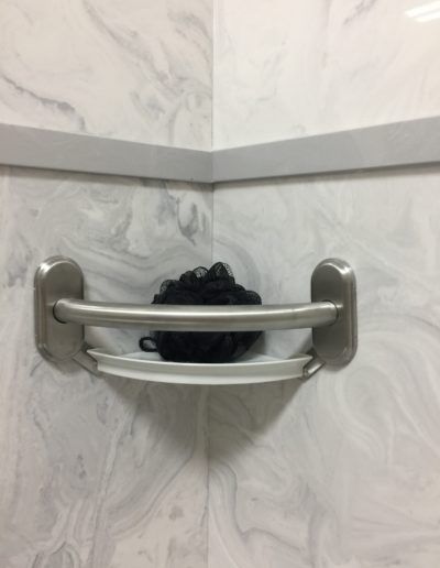 A corner shelf in a bathroom with a black object on it.