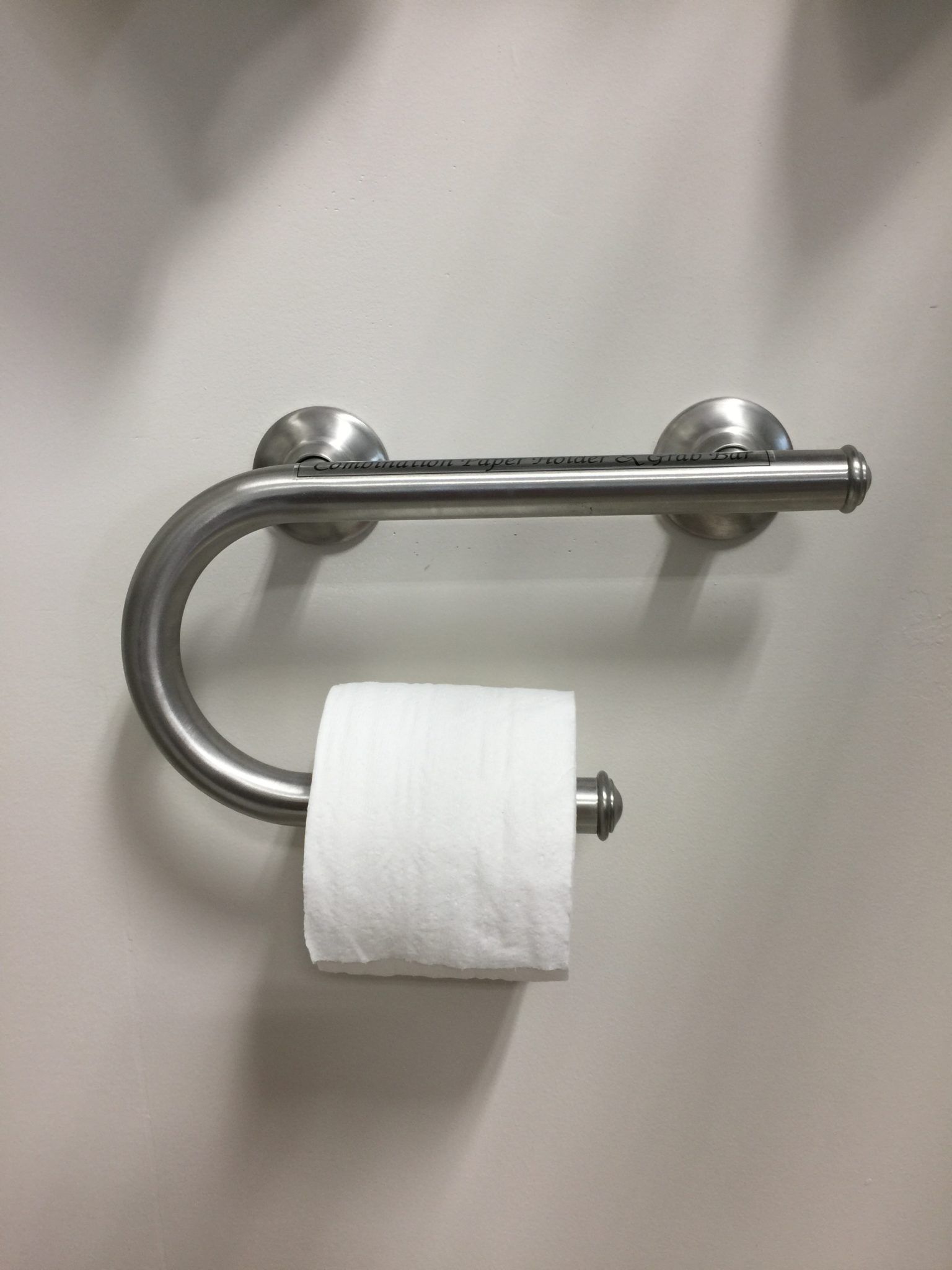 A roll of toilet paper is sitting on a stainless steel toilet paper holder.