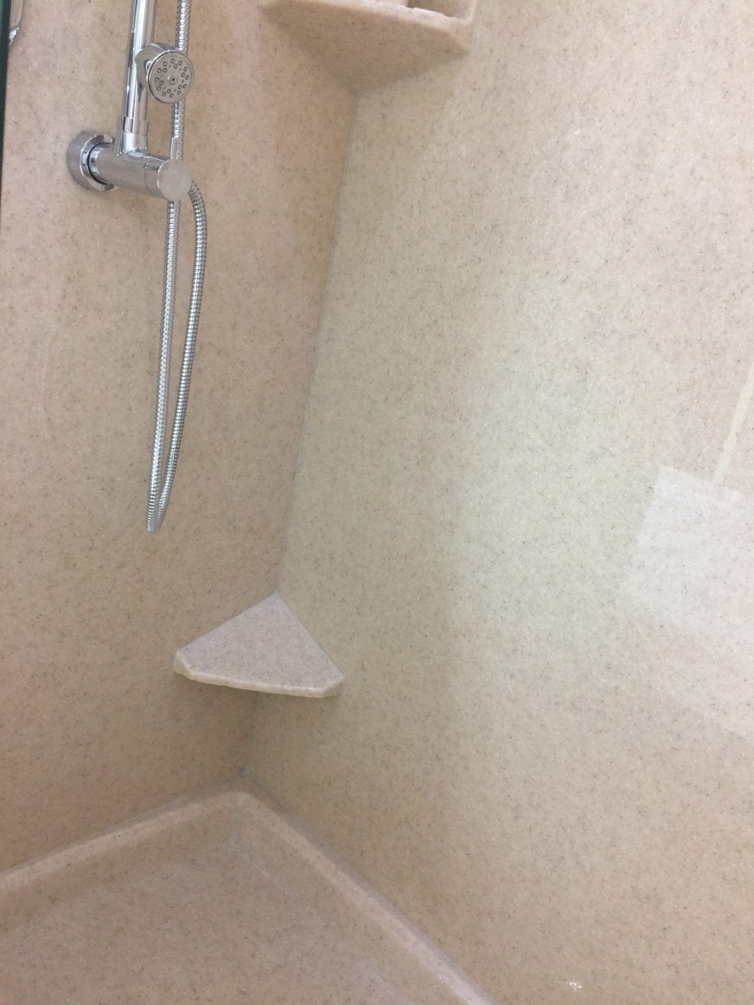 A shower with a corner shelf and a shower head.