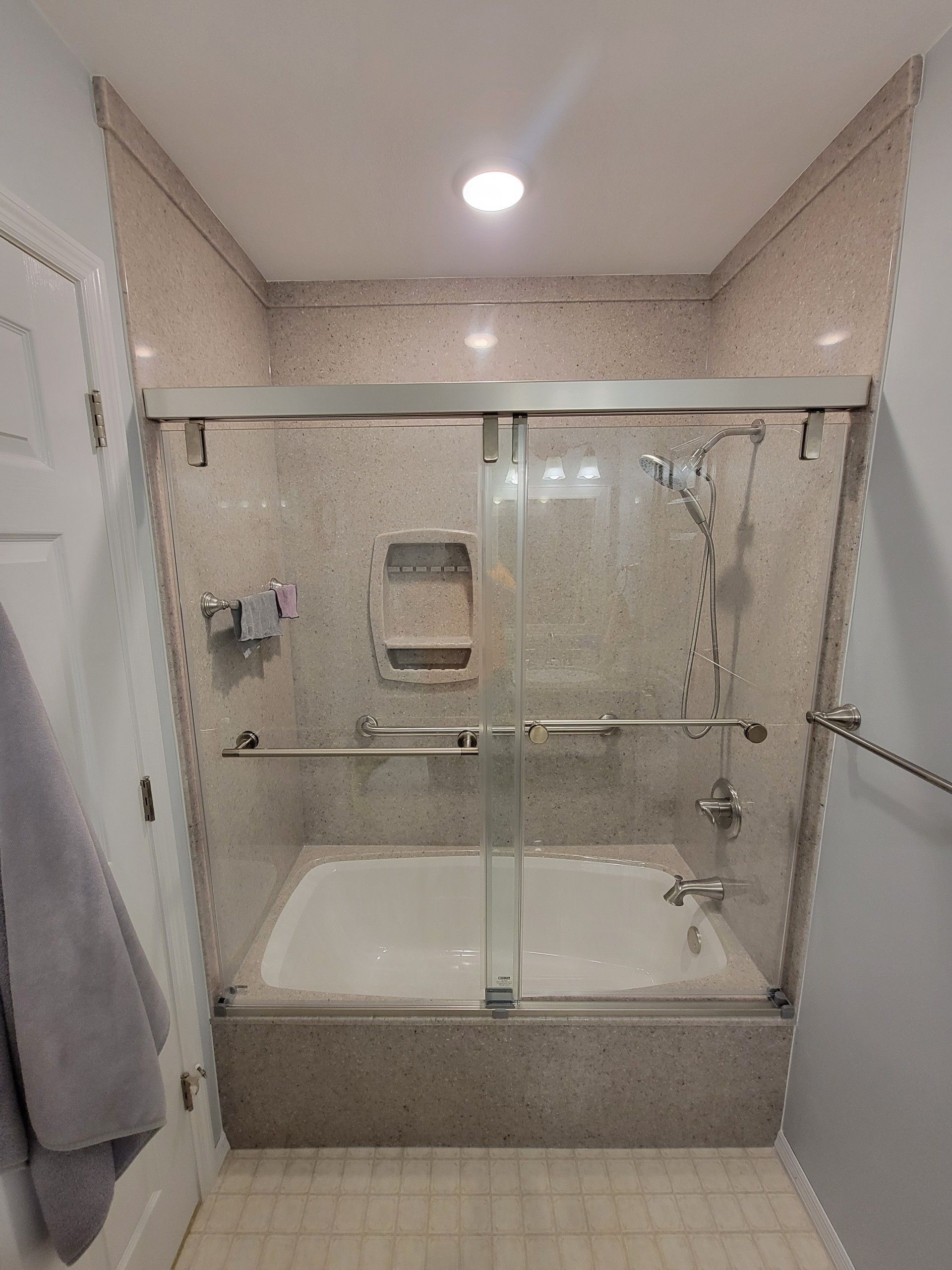 A bathroom with a bathtub and a shower with a glass door.