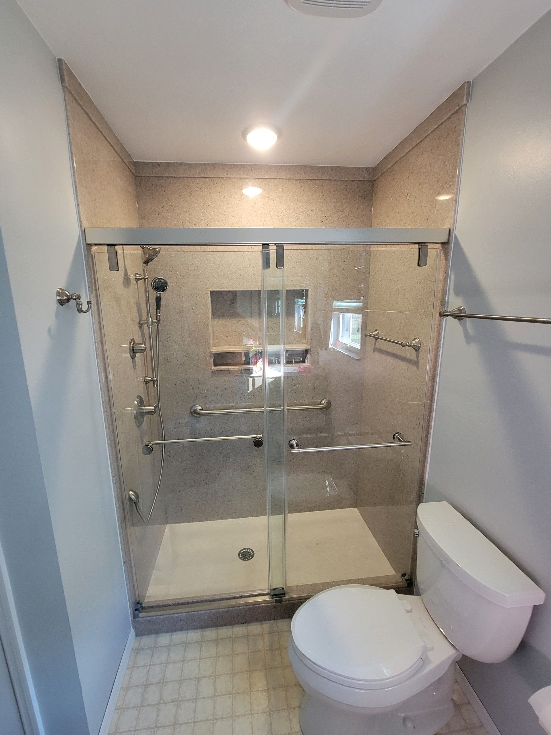 A bathroom with a toilet, shower, and sliding glass door.