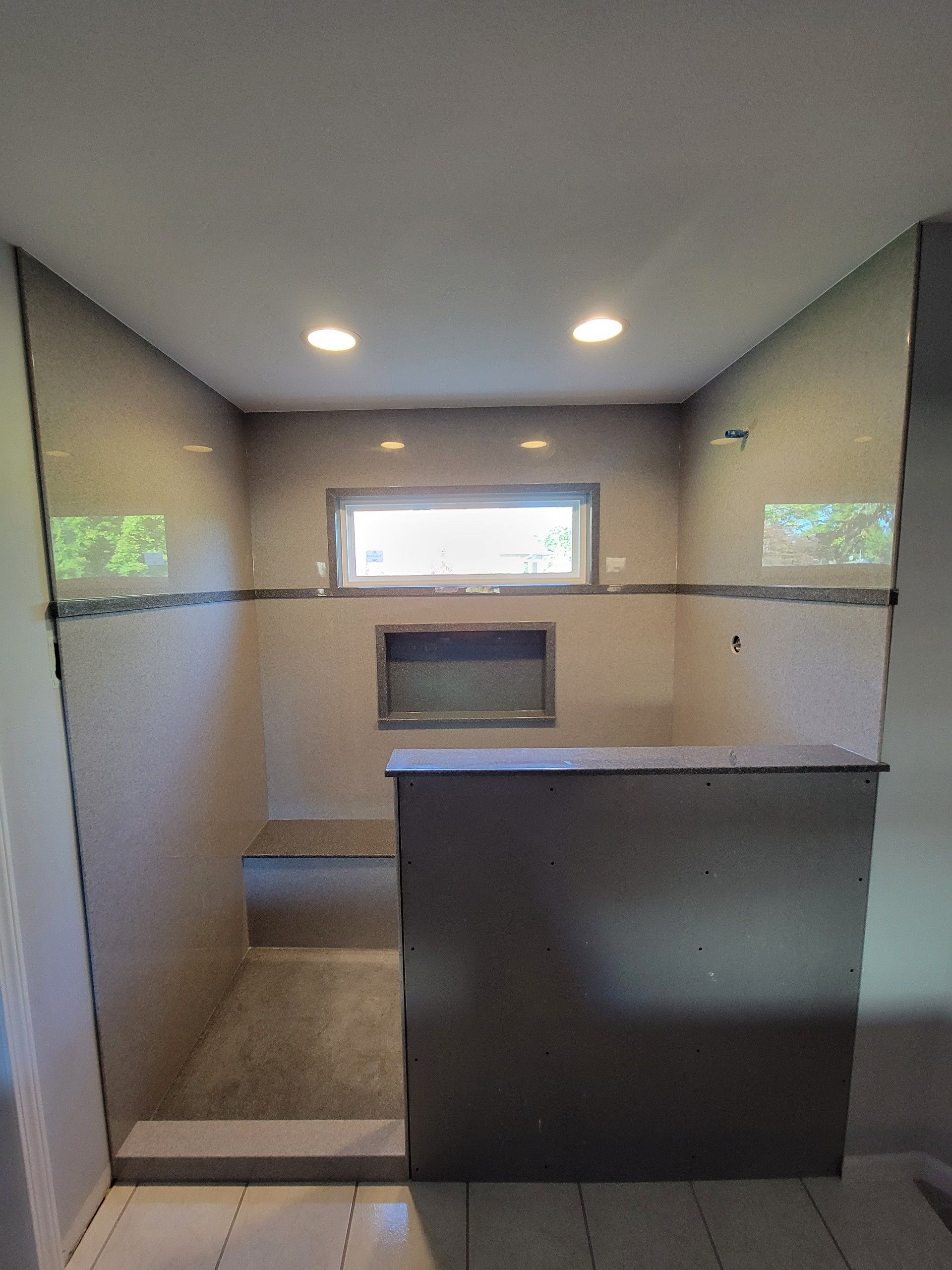 A bathroom with a walk in shower and a window.