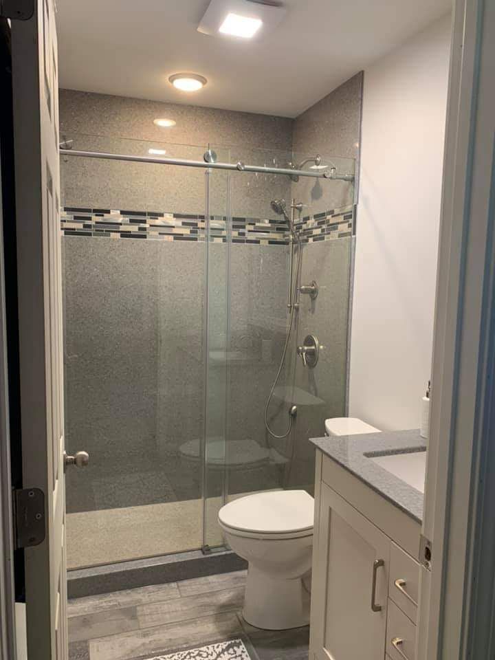 A bathroom with a toilet , sink and walk in shower.