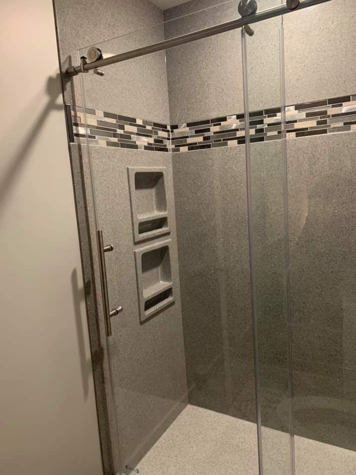 A bathroom with a sliding glass shower door and a tiled wall.