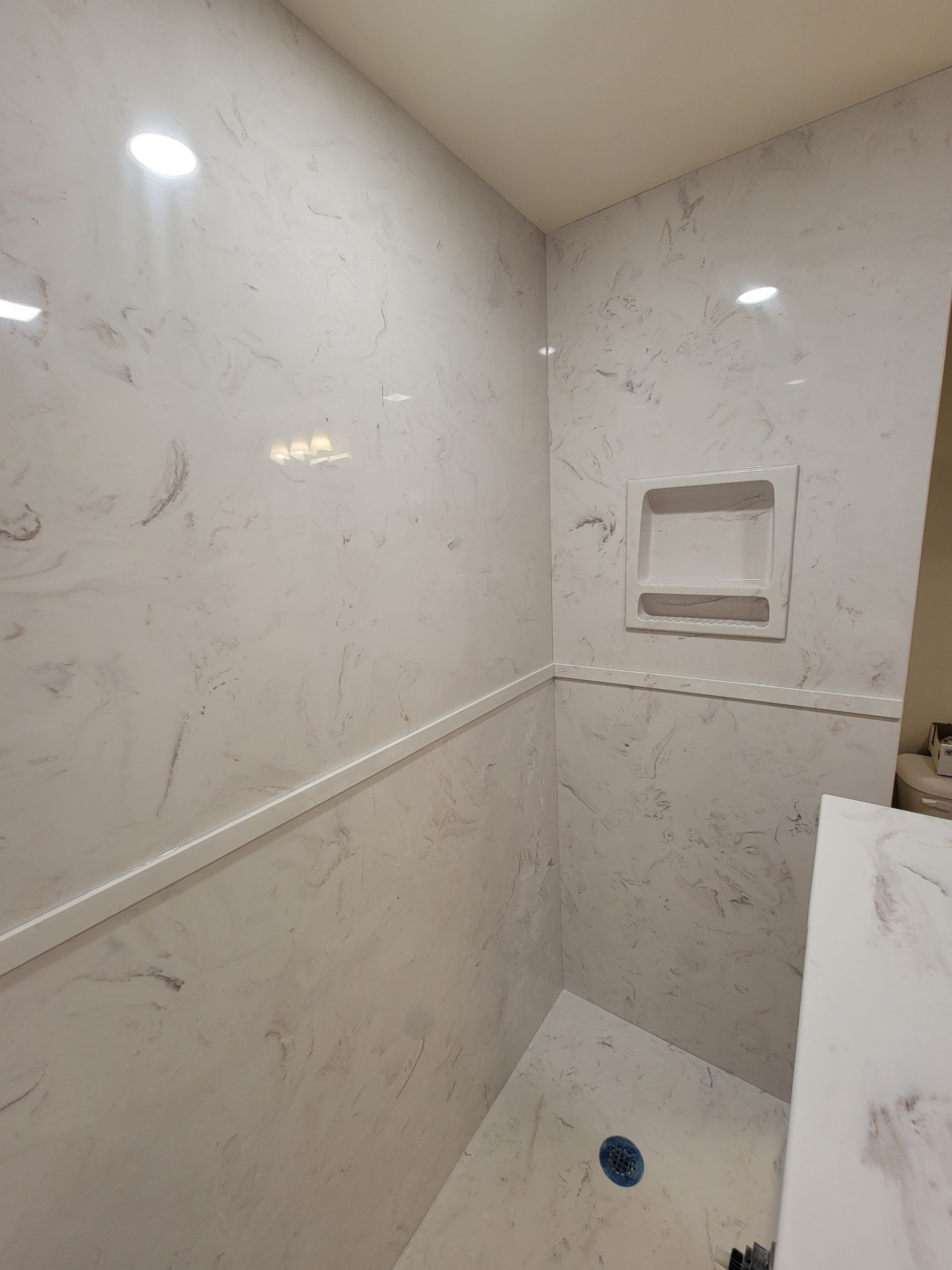 A bathroom with marble walls and a walk in shower.