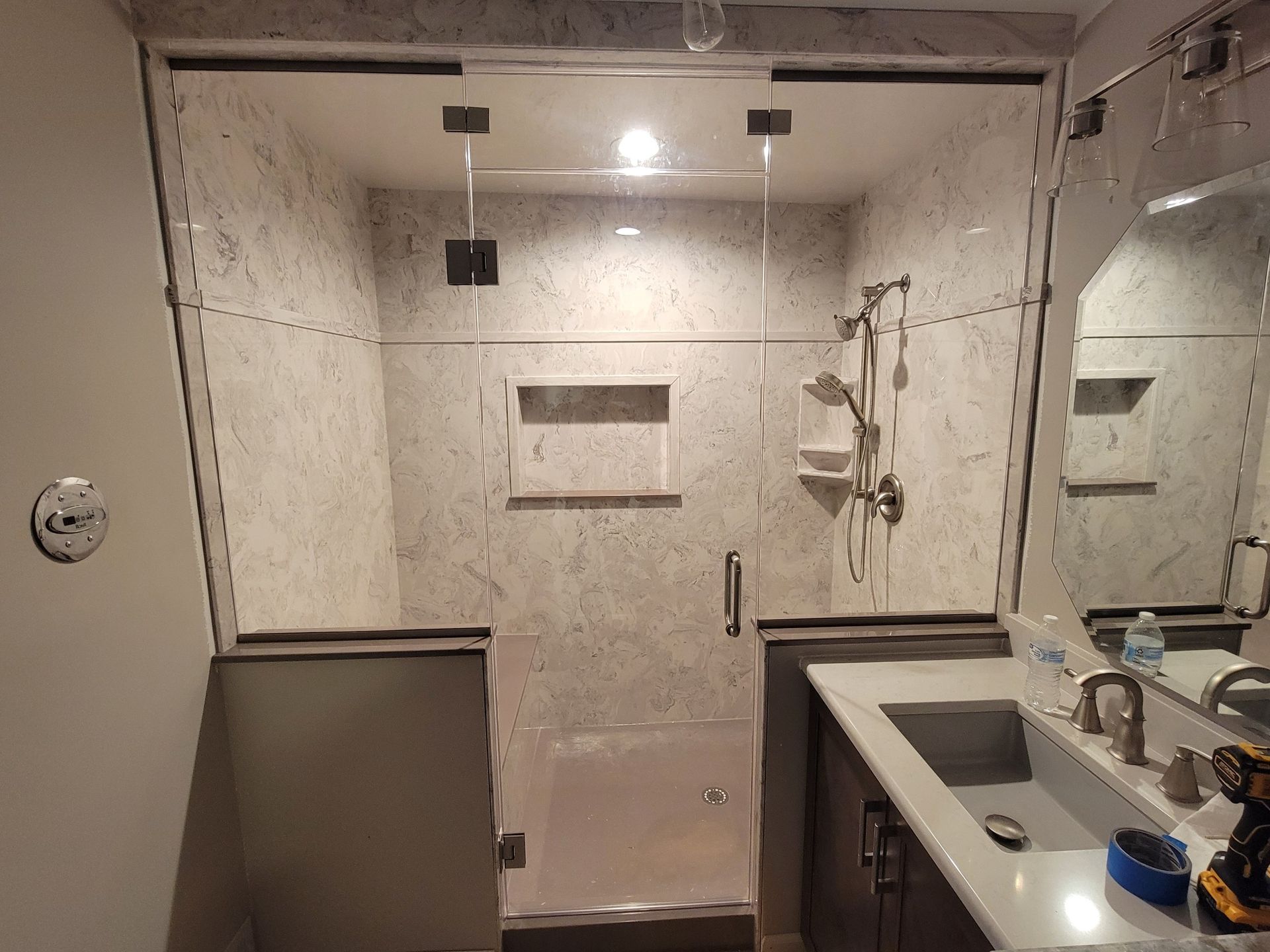 A bathroom with a walk in shower, sink and mirror.