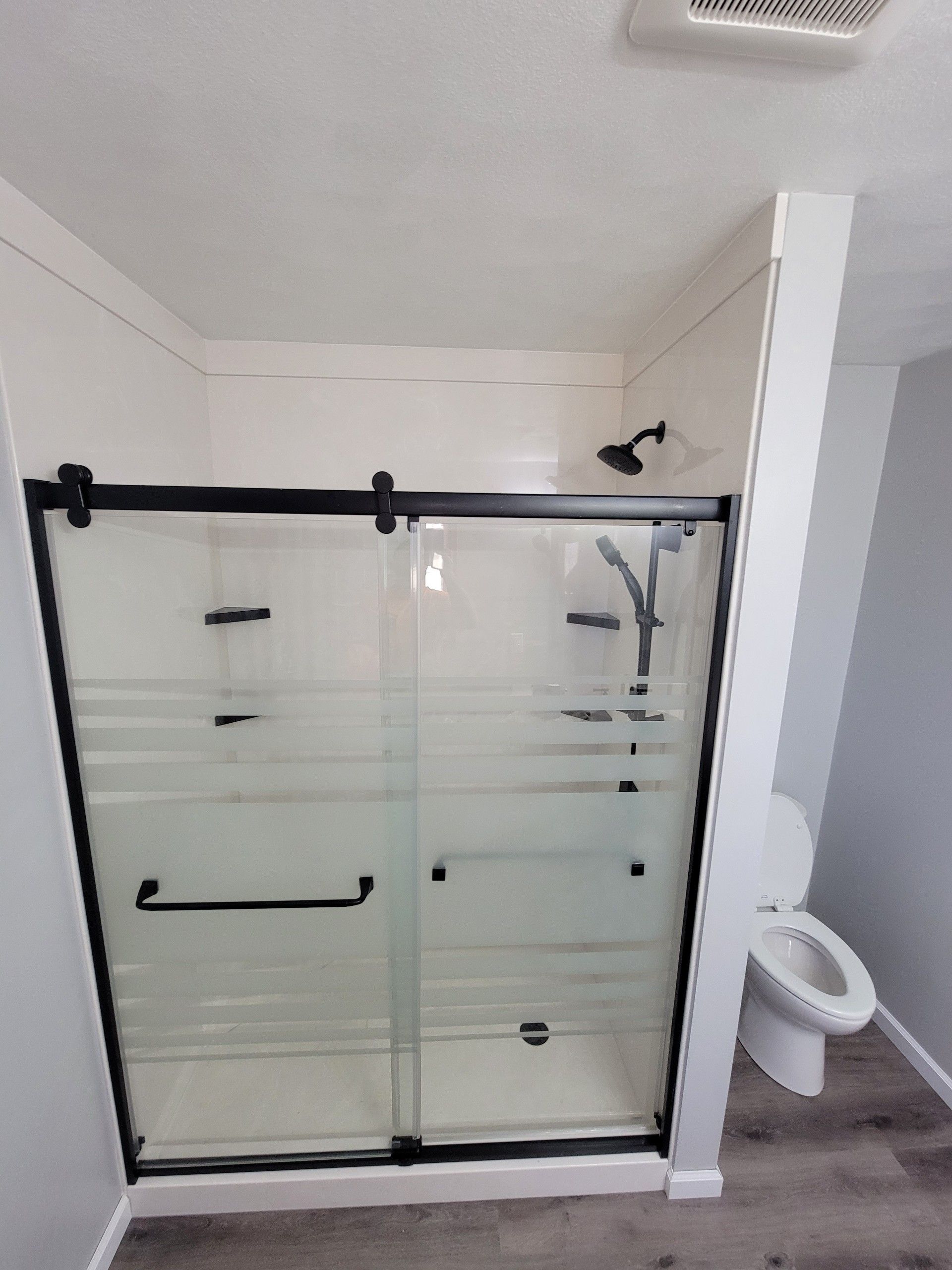 A bathroom with a sliding glass shower door and a toilet.
