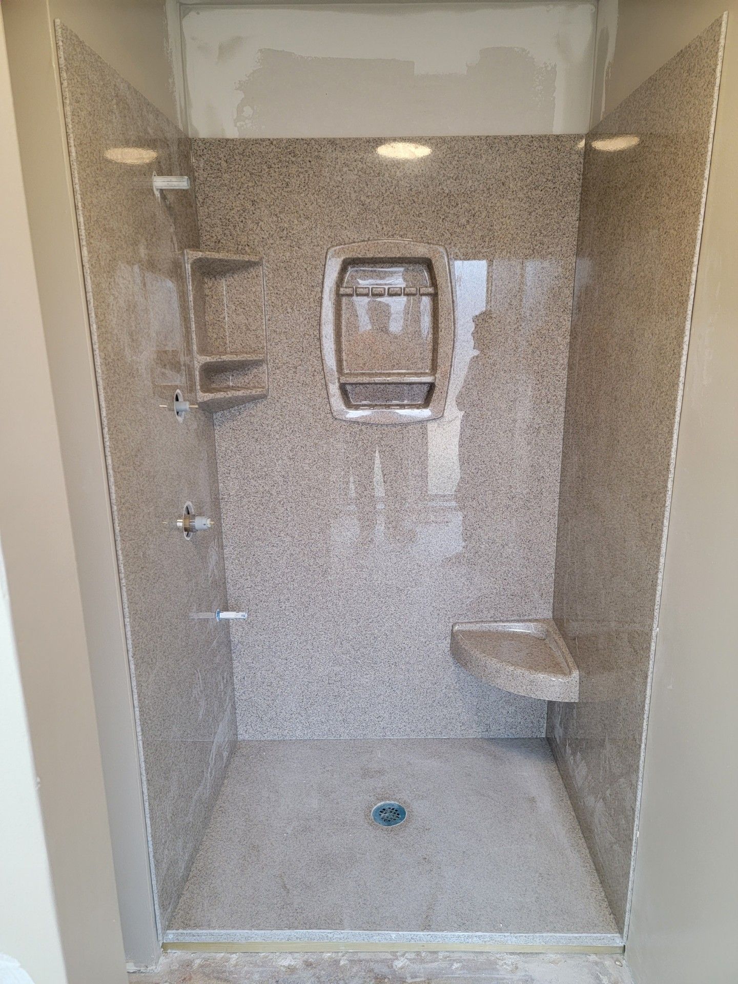 A walk in shower with a seat and shelves in a bathroom.